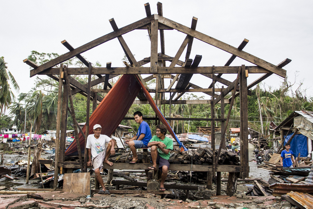 Men taking a break from their construction work under an aid tarp. Lack of strict building codes and simple house designs mean that many houses destroyed by Typhoon Haiyan can be rebuilt fairly quickly.