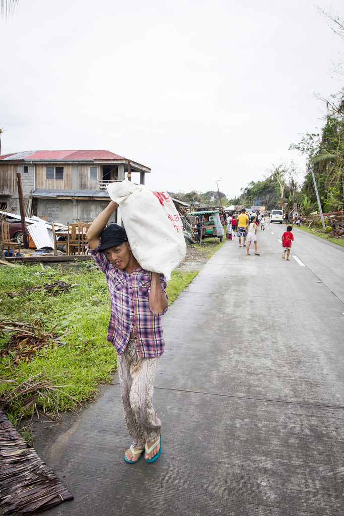 A man carries a bag of rice, distributed by the Filipino army in the wake of Typhoon Haiyan, back to his house in Veloso, Samar. 
