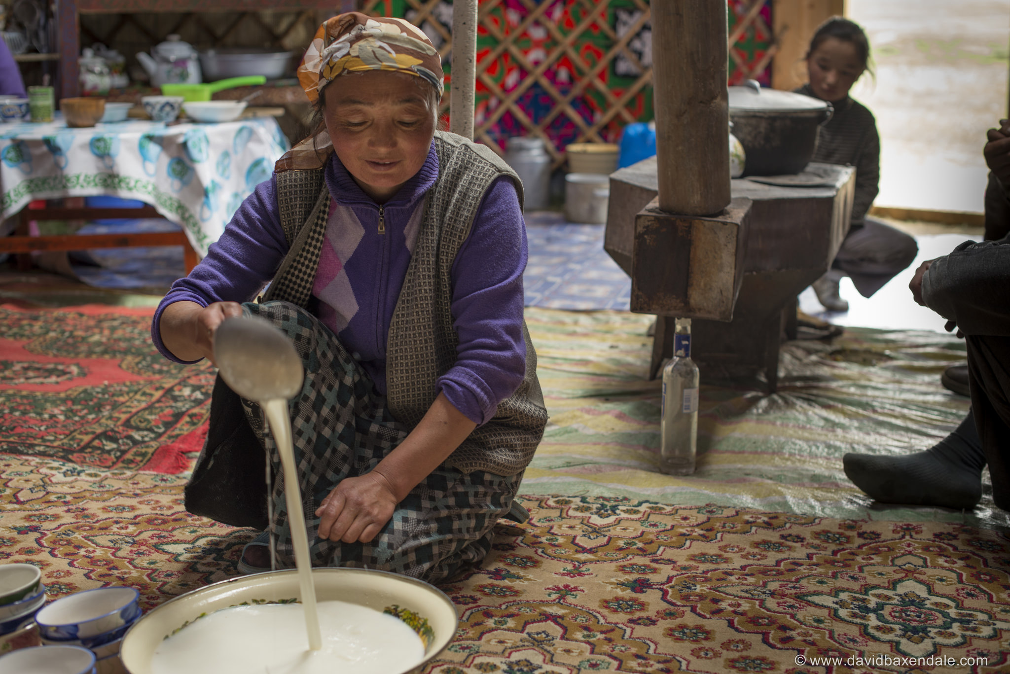 As in many places the world over, alcohol plays a central role in Mongolian life. This woman is pouring fermented mare's milk to make a ubiquitous alcoholic beverage called Airag (or Kumis) while an empty vodka bottle supports the stove behind her. Photo courtesy of www.david baxendale.com