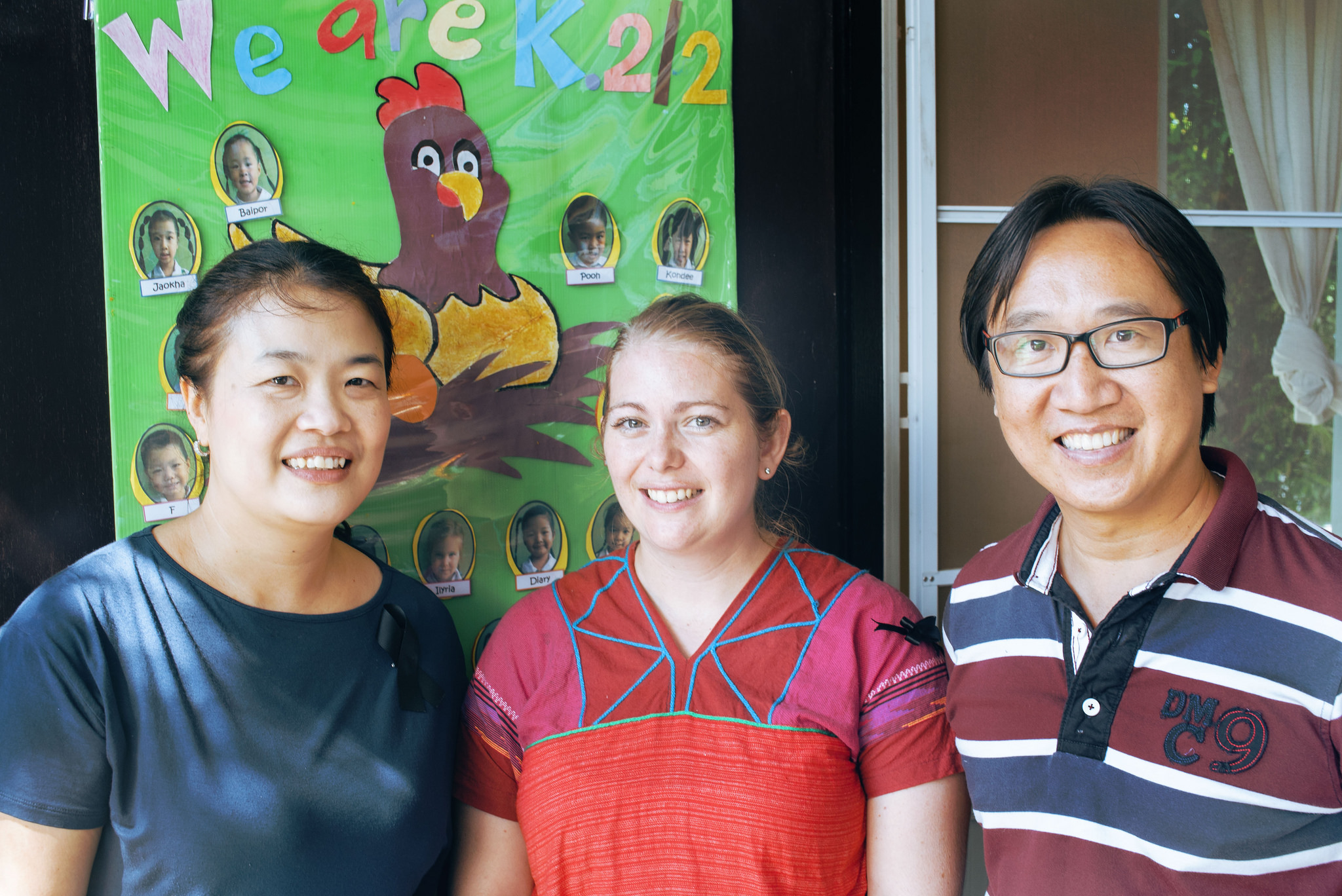 Mary poses with Kruu Amm and Khruu Dom, the husband and wife duo who founded Good Kids. Amm and Dom originally ran a foster home for orphaned children from their small community (some of whom are now teachers at the school) and decided a bilingual preschool would be a natural extension of this work - Photo by Chad Loftis.