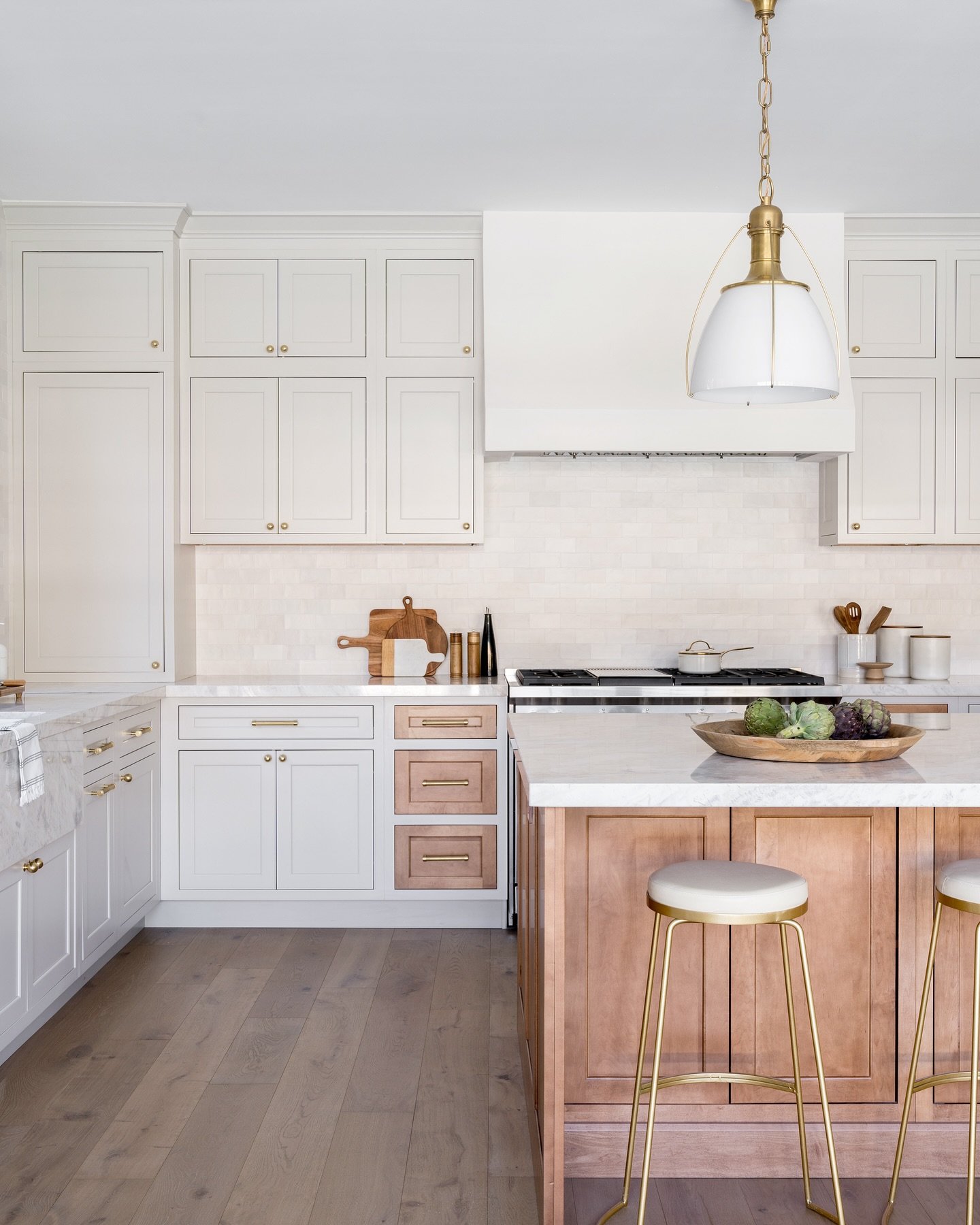 Did we mention how much we love it when our clients want to take risks? 
This two-toned kitchen has so much personality and is the perfect blend of old meets new. Sleek cream and oak cabinets create a contemporary feel, while the brass hardware adds 