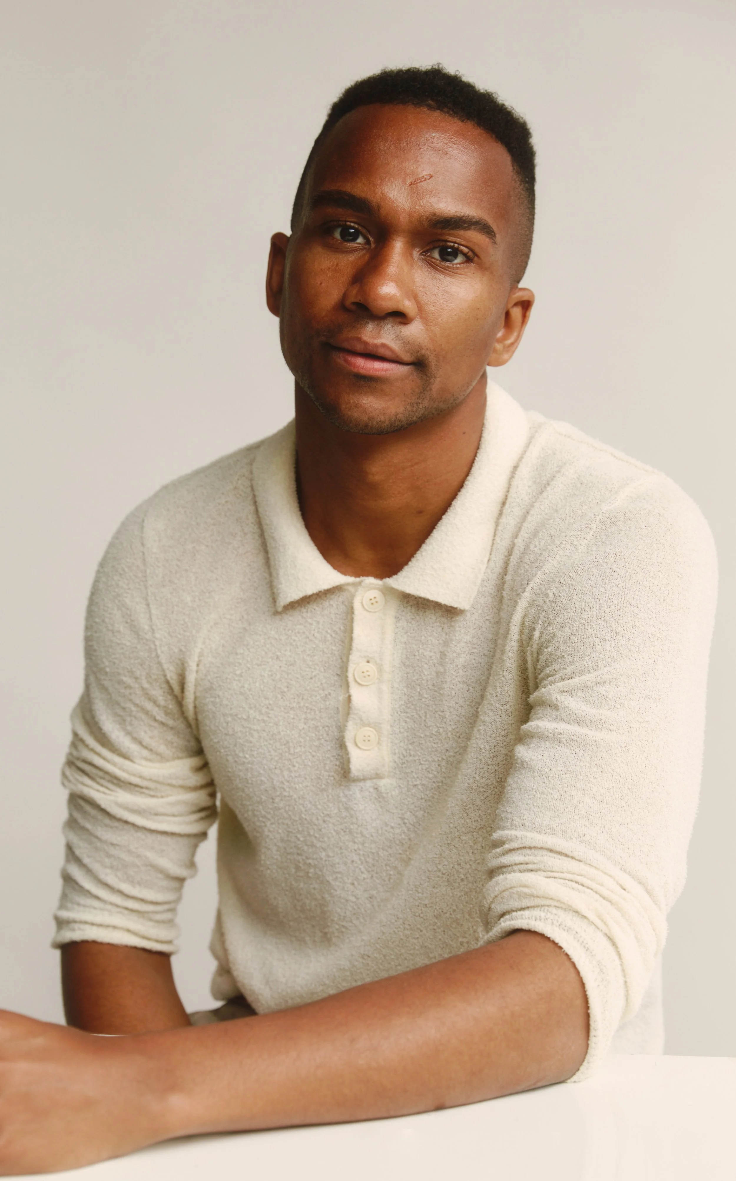 Photo of Rob Franklin, a Black man in his early thirties, in a cream colored long sleeved polo shirt.