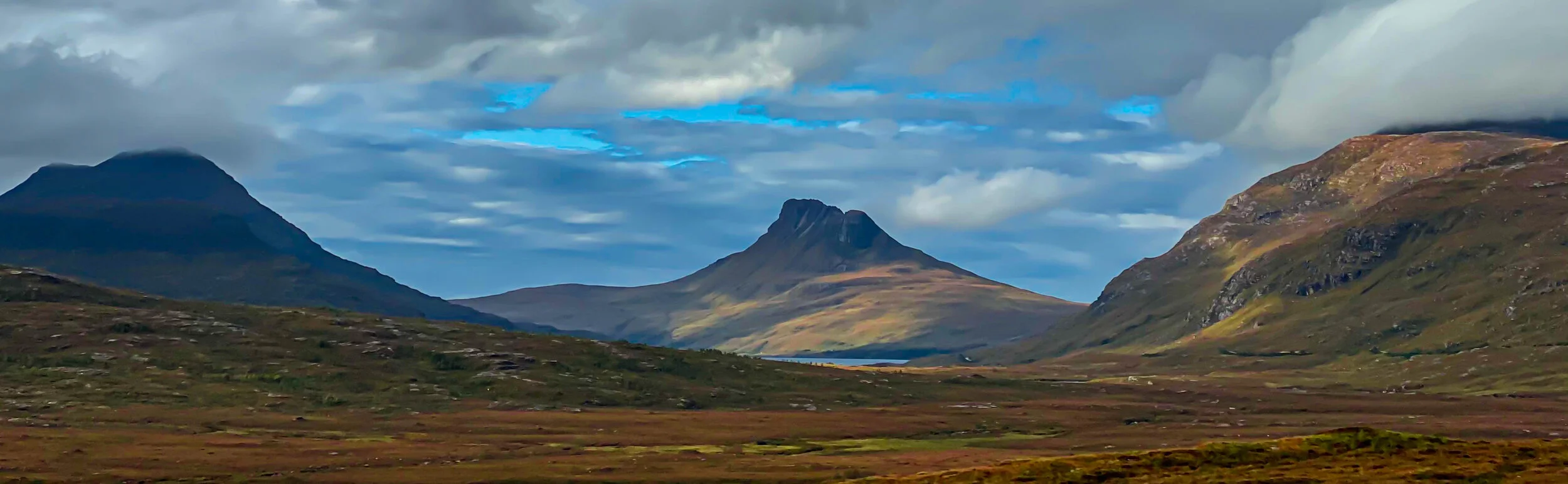 Stac Pollaidh in the middle with Beinn an Eoin on the left with its summit covered in cloud.