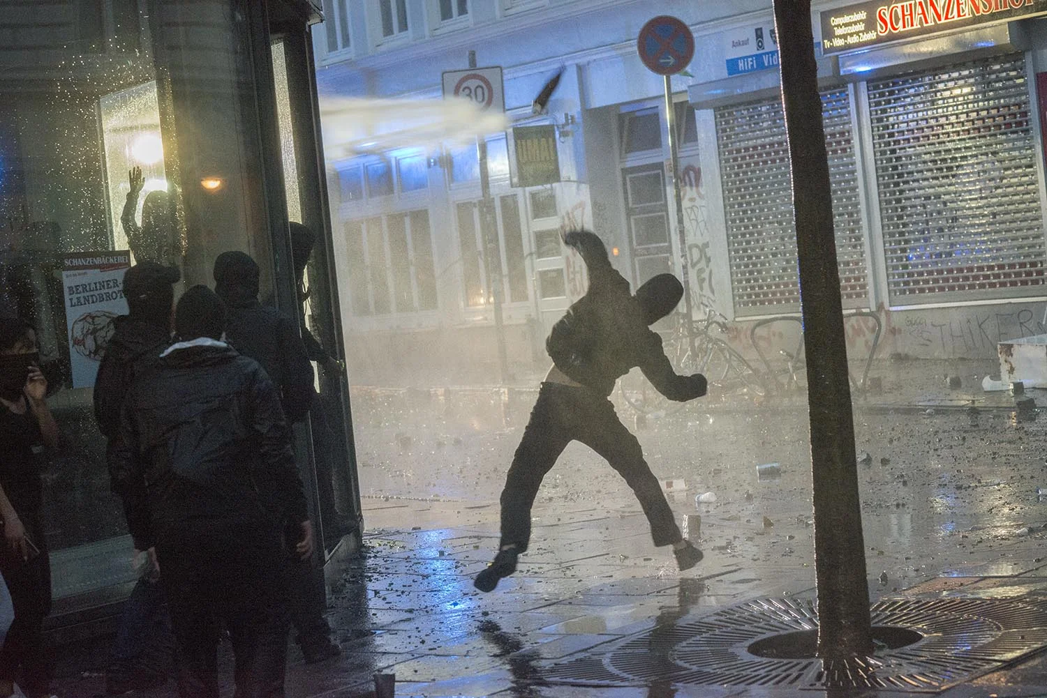 One of the riot-tourists is throwing a bottle against the watecannons of Hamburg’s police force.