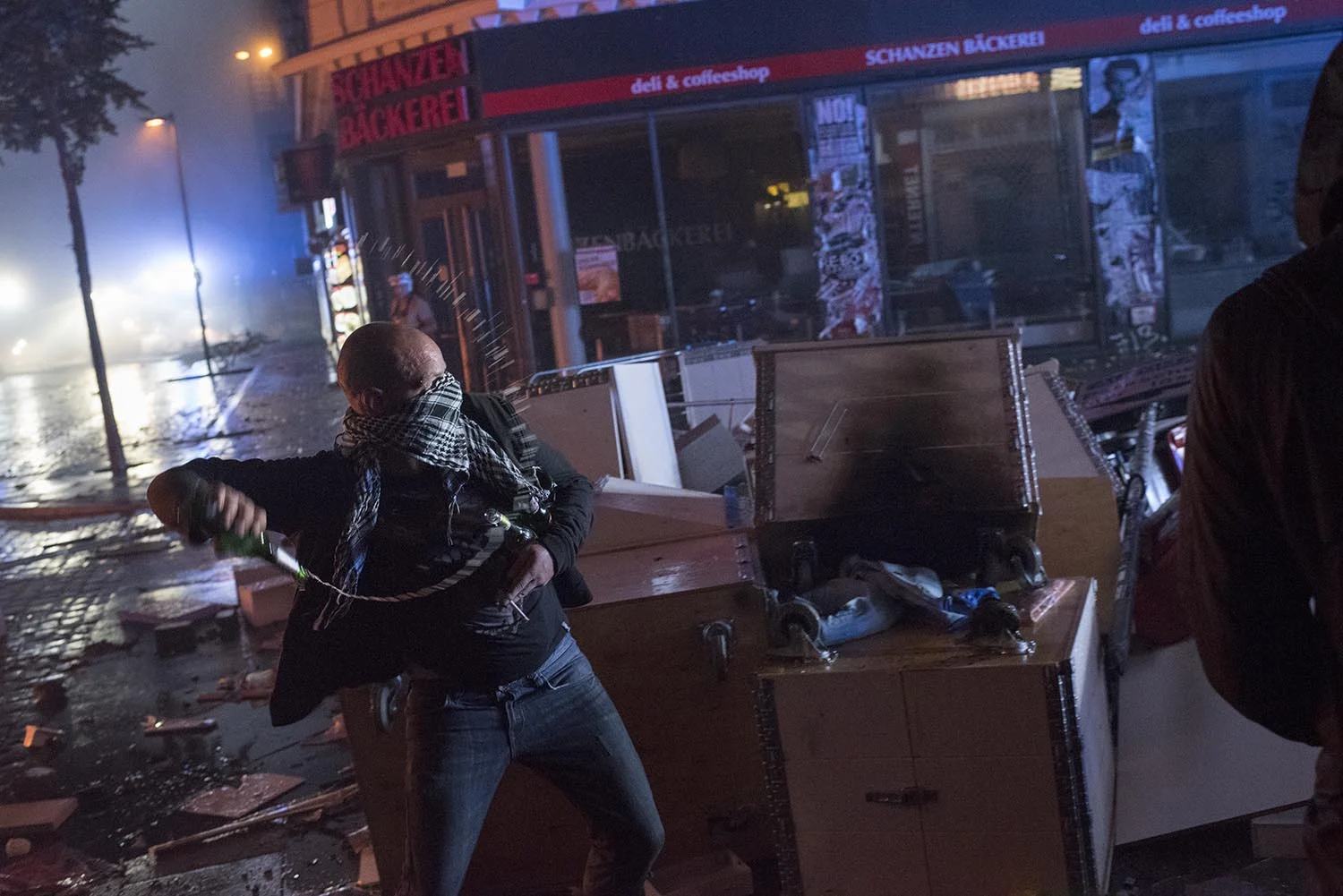 This hooded demonstrator with his bottle of beer is fighting against the international police with their modern water cannons. And his cigarette is still burning.