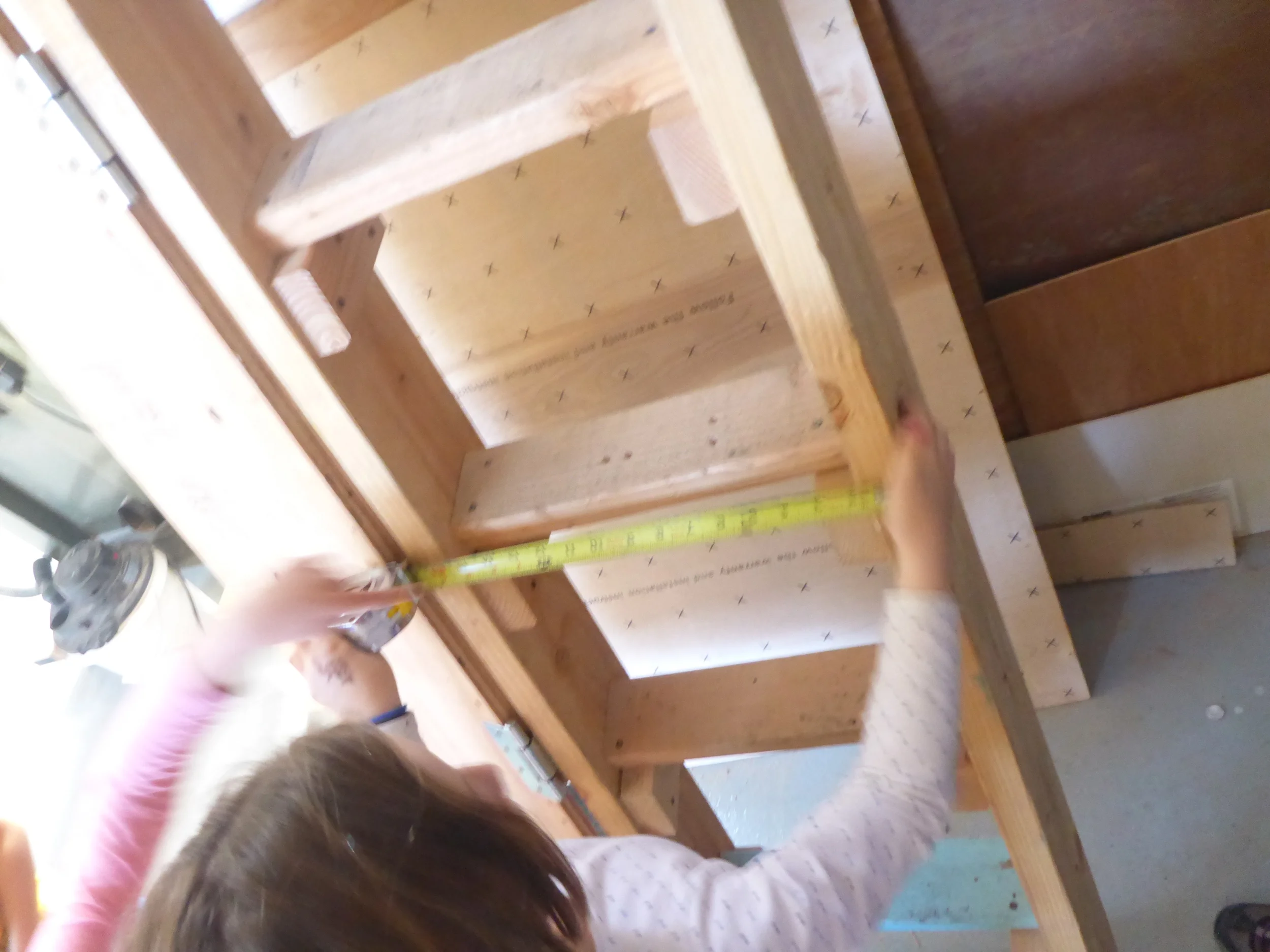 Using what works. Miel spots an existing ladder in the shop and decides to use it to help guide her measurements to determine rung length. 