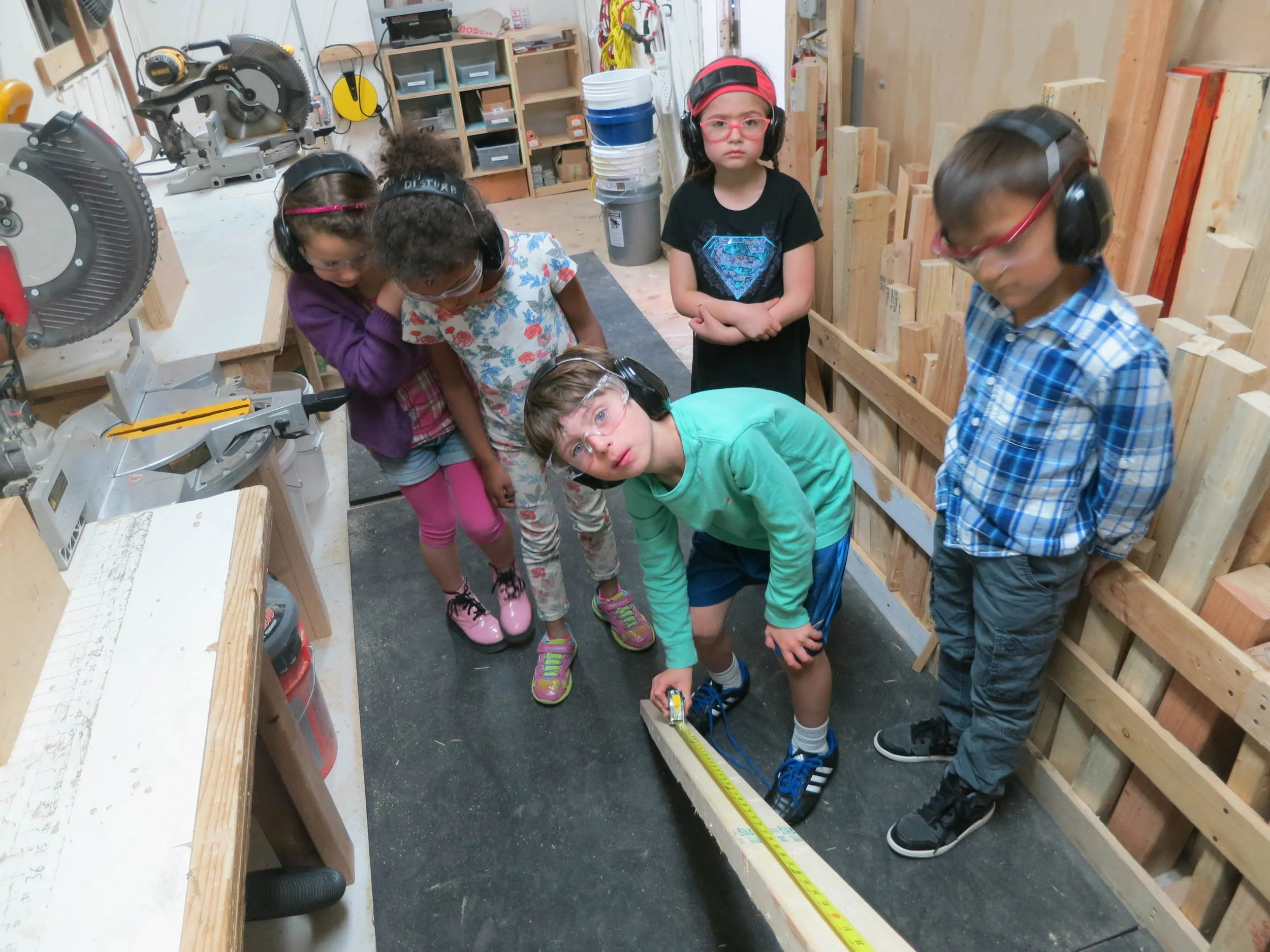 Measurements translate into marks. Tinkers measure scraps of wood looking for one long enough to mark the ladders first vertical length to be cut on the chop saw. 