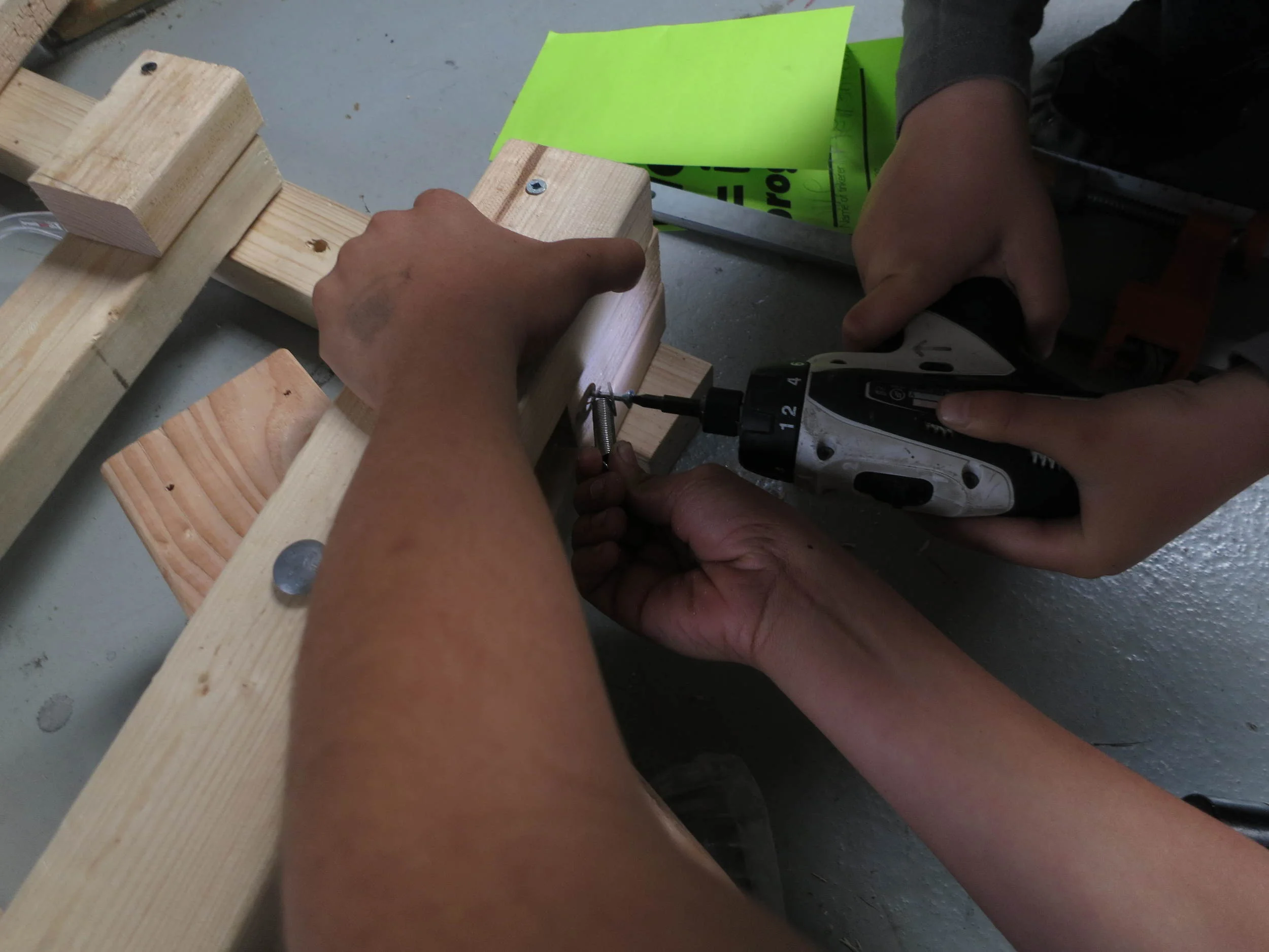 Working together to install a tension spring to the base of the lever arm. 