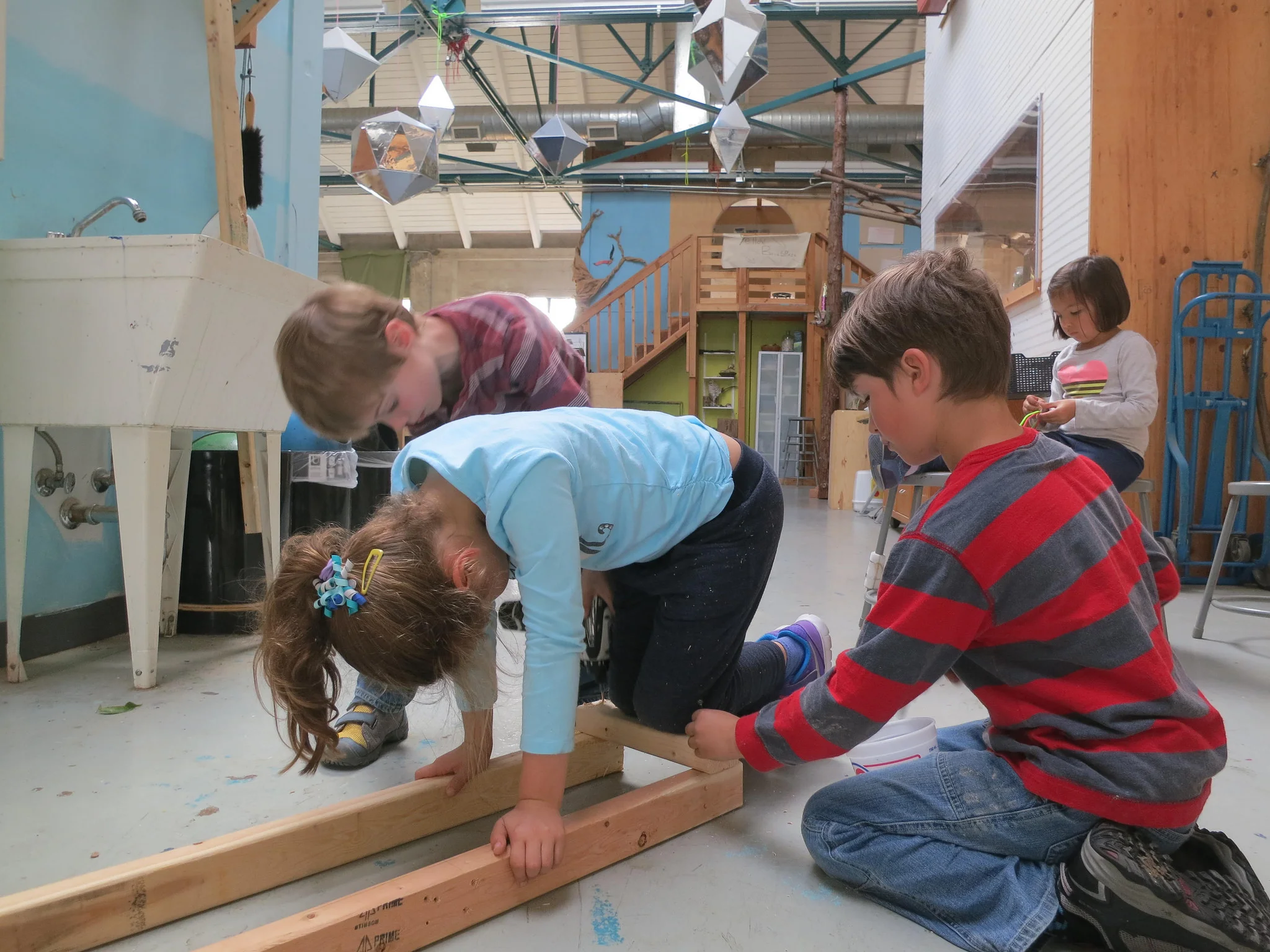 Natalie uses her body weight to hold the pieces flush while Adrian and Isaac drive screws to attach the ties to the track. 