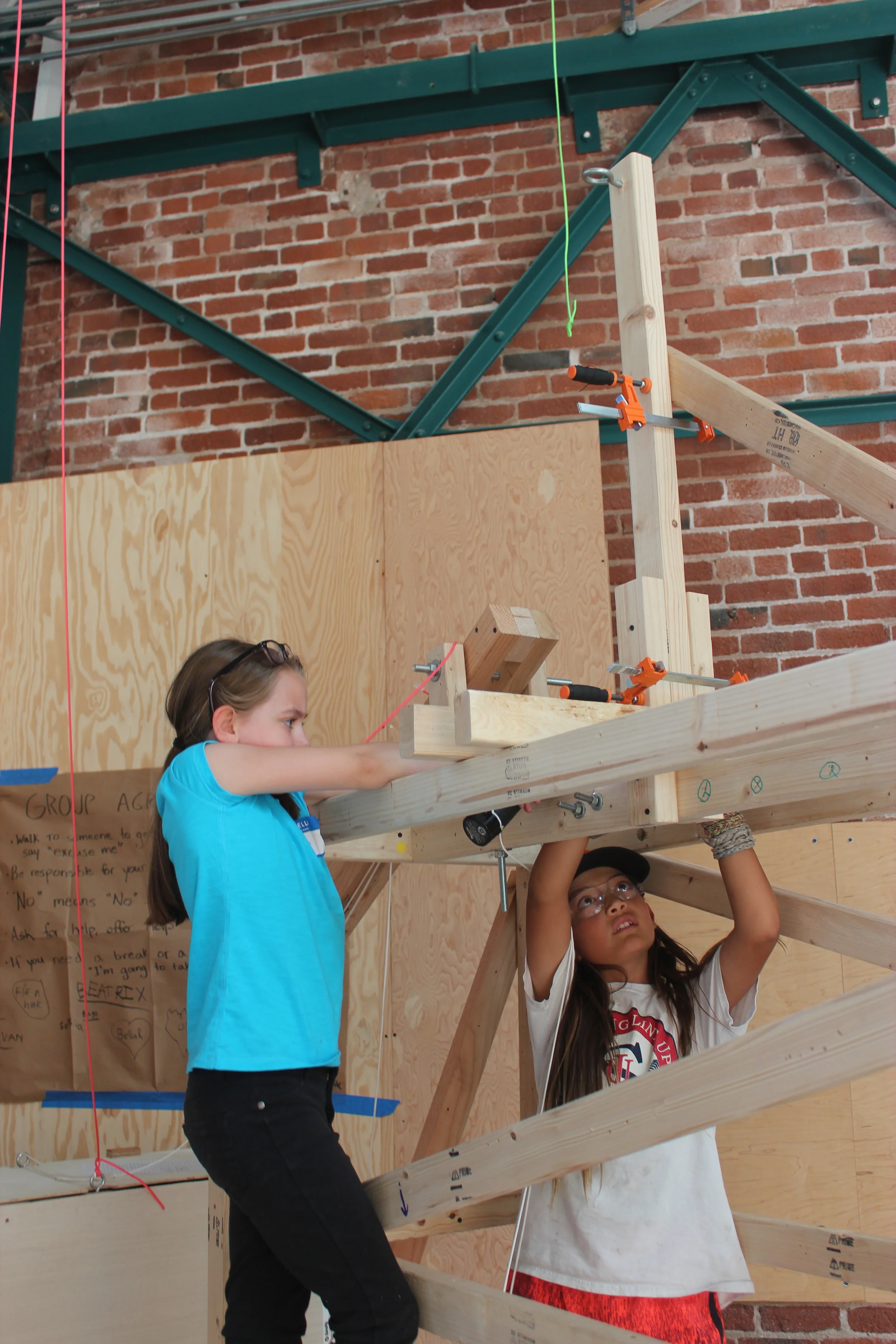 Helen and Justin diligently continue their work on the crane's lifting mechanism. 