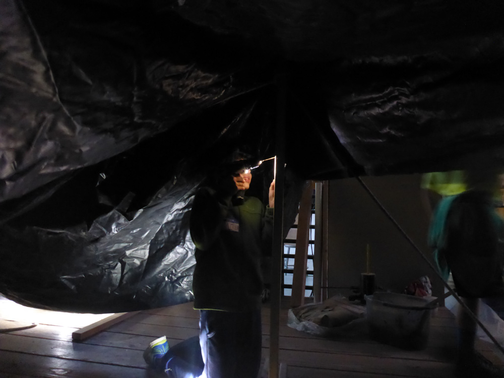 Working by the light of the drill to add screws to the tent supports.