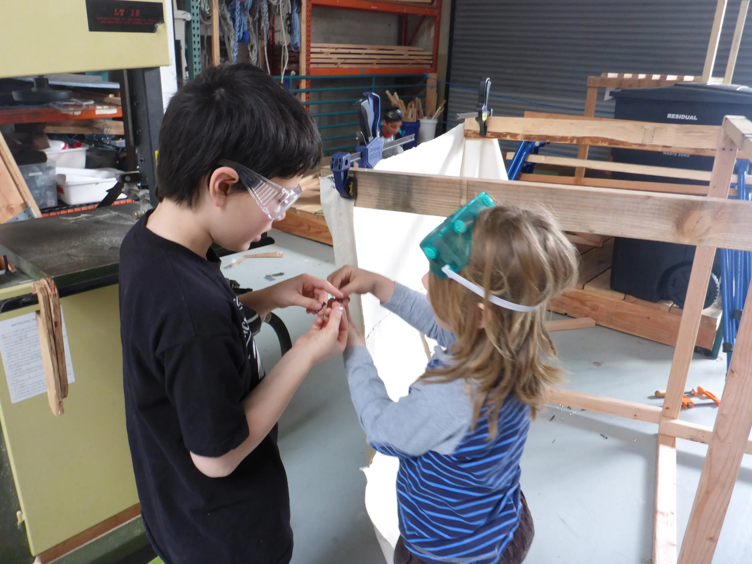 Ayden shows Eli how to put the finish washer and screws together to attach the awning.