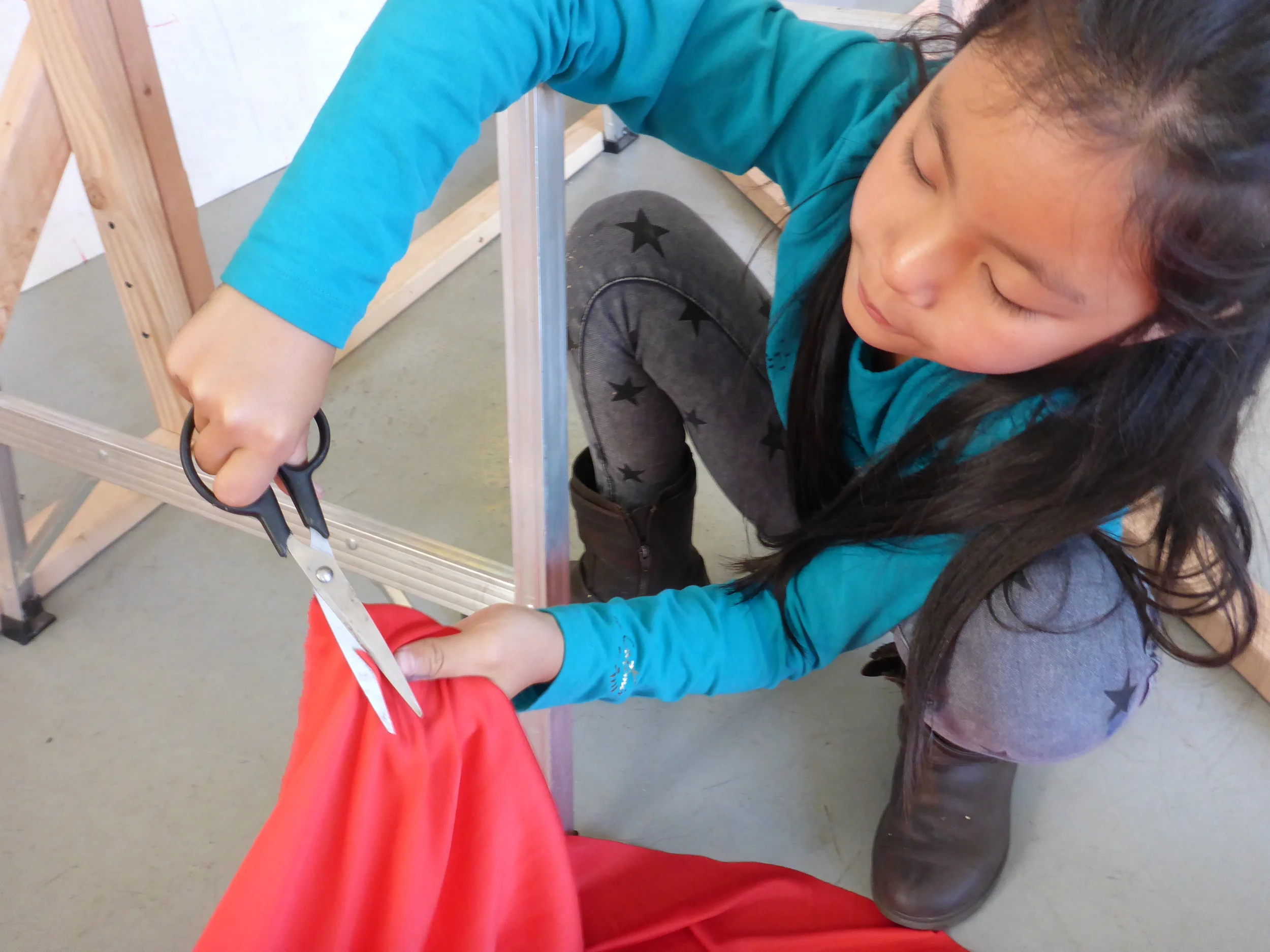 Clarise snips a hole in the fabric so the screws don't get tangled in it!