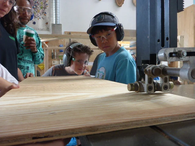 Lyosha concentrates super hard at lining up a cut on the bandsaw with the help of Matthew and Lena. 