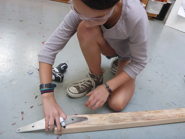 Pearl marks where her team needs to drill holes to attach a hinge to the target.