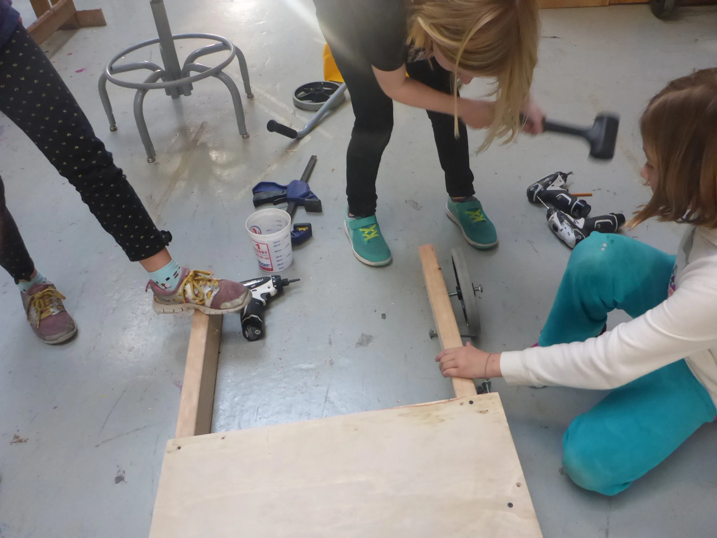 Kaya and Q install wheels on the kid- powered car.