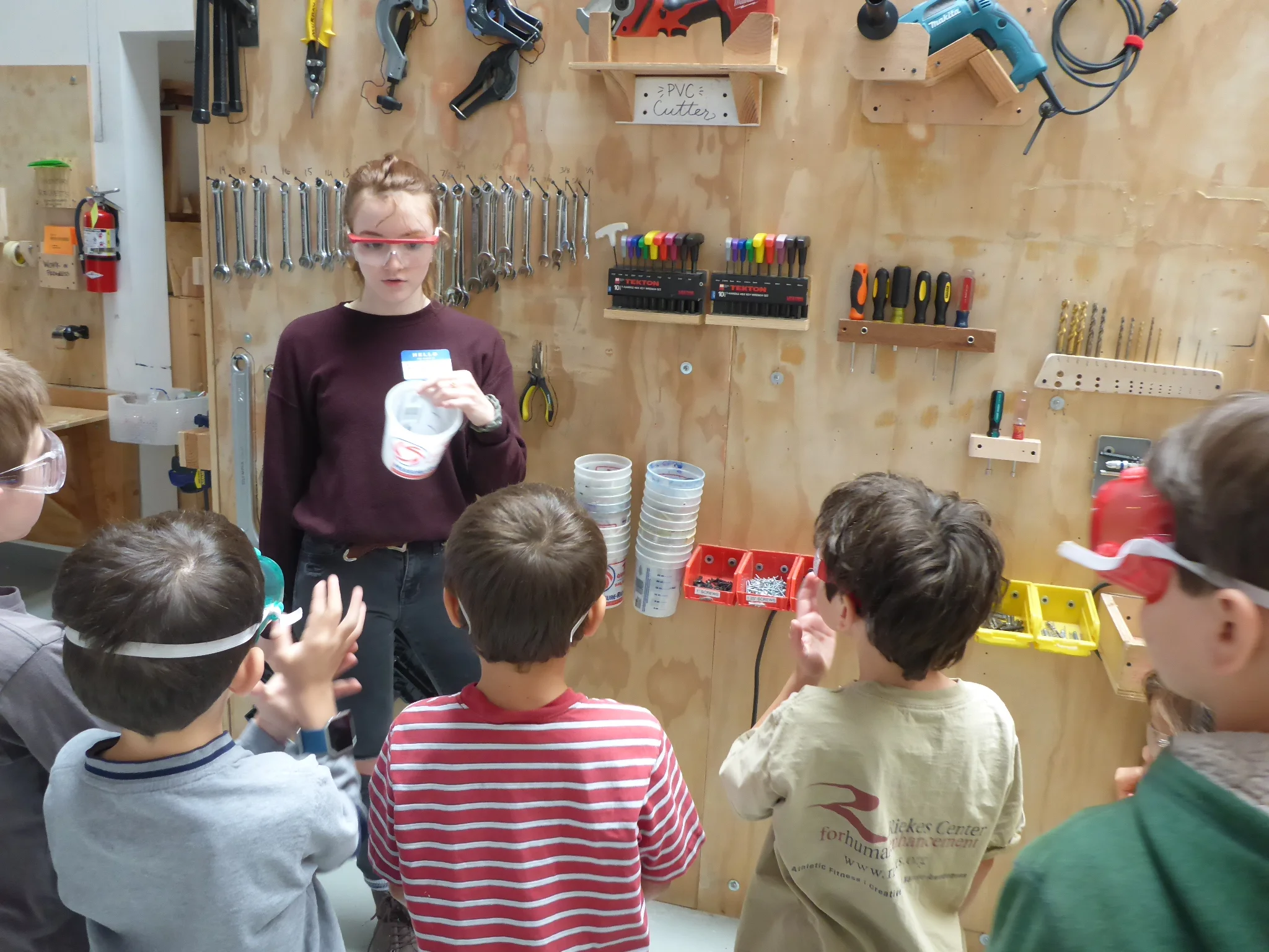 Frannie instructs a group of Tinkerers in the safe use of the drills, the location of the tools they will need, and how to keep pesky screws from rolling away (buckets!) while working on the floor of the warehouse.
