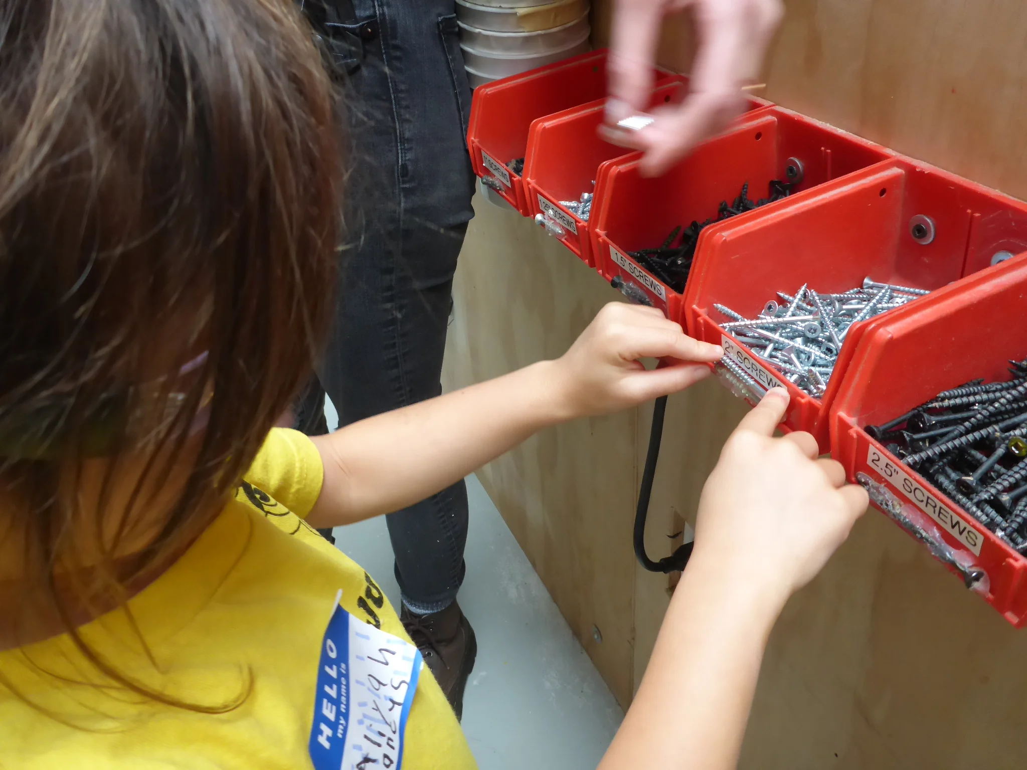 Aliyah inspects the different screw sizes to determine which is appropriate for the thickness of wood we're using.