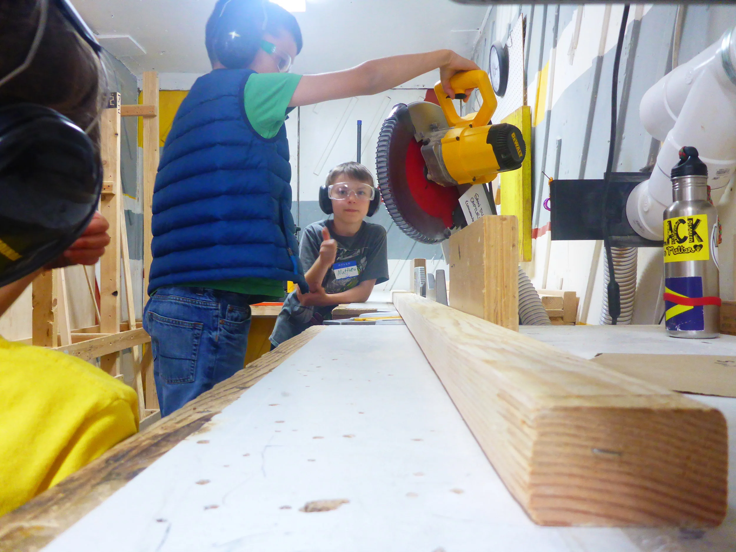 Adrian adjusts the chopsaw and checks the angle before cutting some bracers for the afternoon project. Because of how intense it is to be in the chopsaw room cutting components, the attention of all the Tinkerers is required before we turn the saw on.
