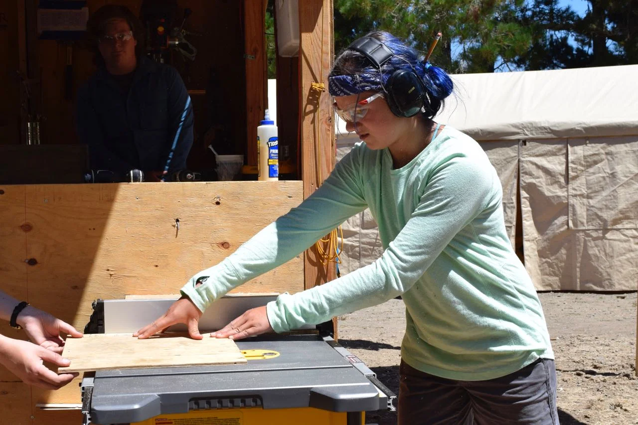 Blueberry tries out the table saw for the first time to cut a bottom for a pulley-powered basket.
