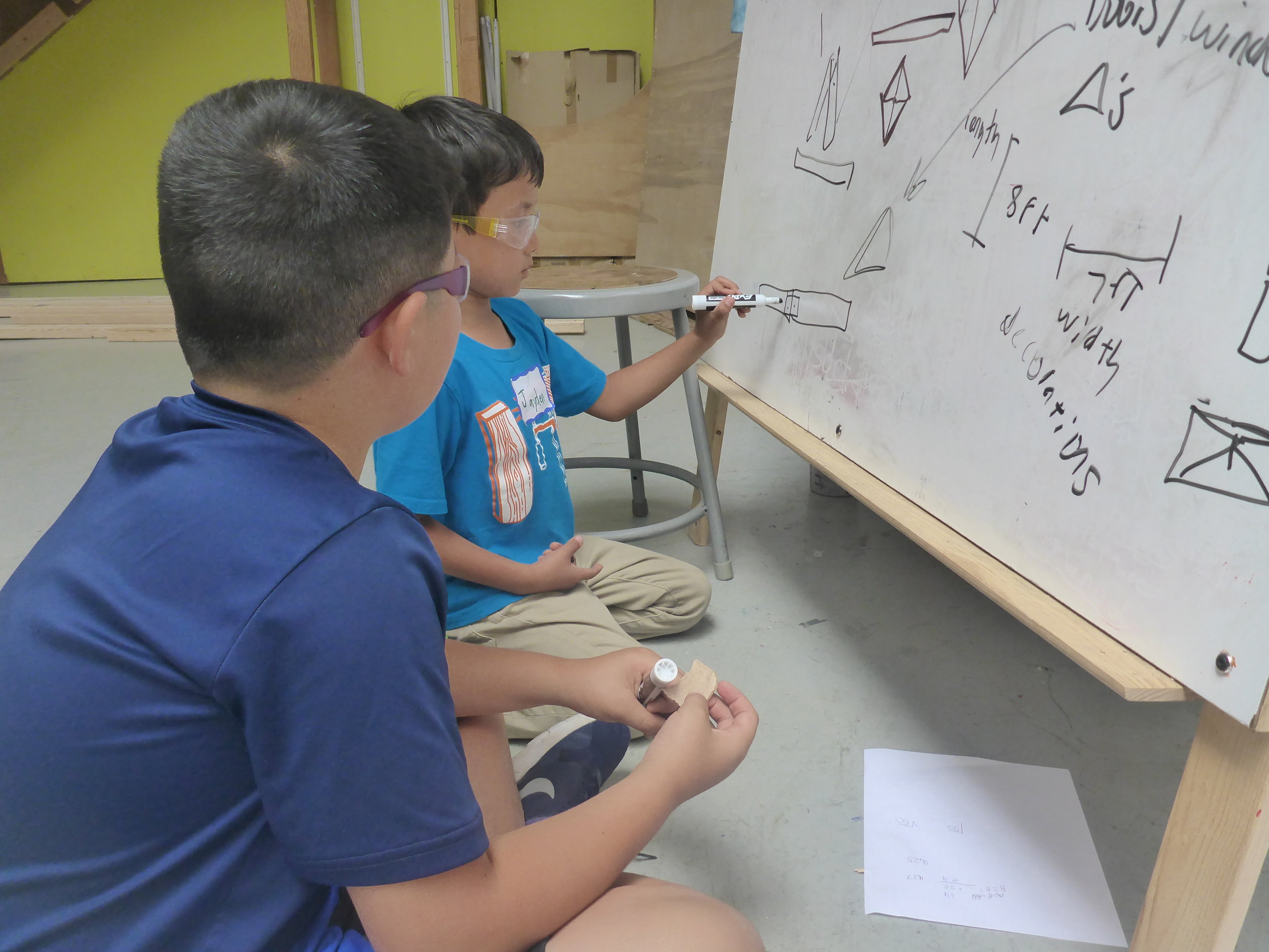 Jayden makes a drawing to show Ethan how they'll be able to connect two shorter pieces to make the extra long board for the sides of the pyramid.&nbsp;