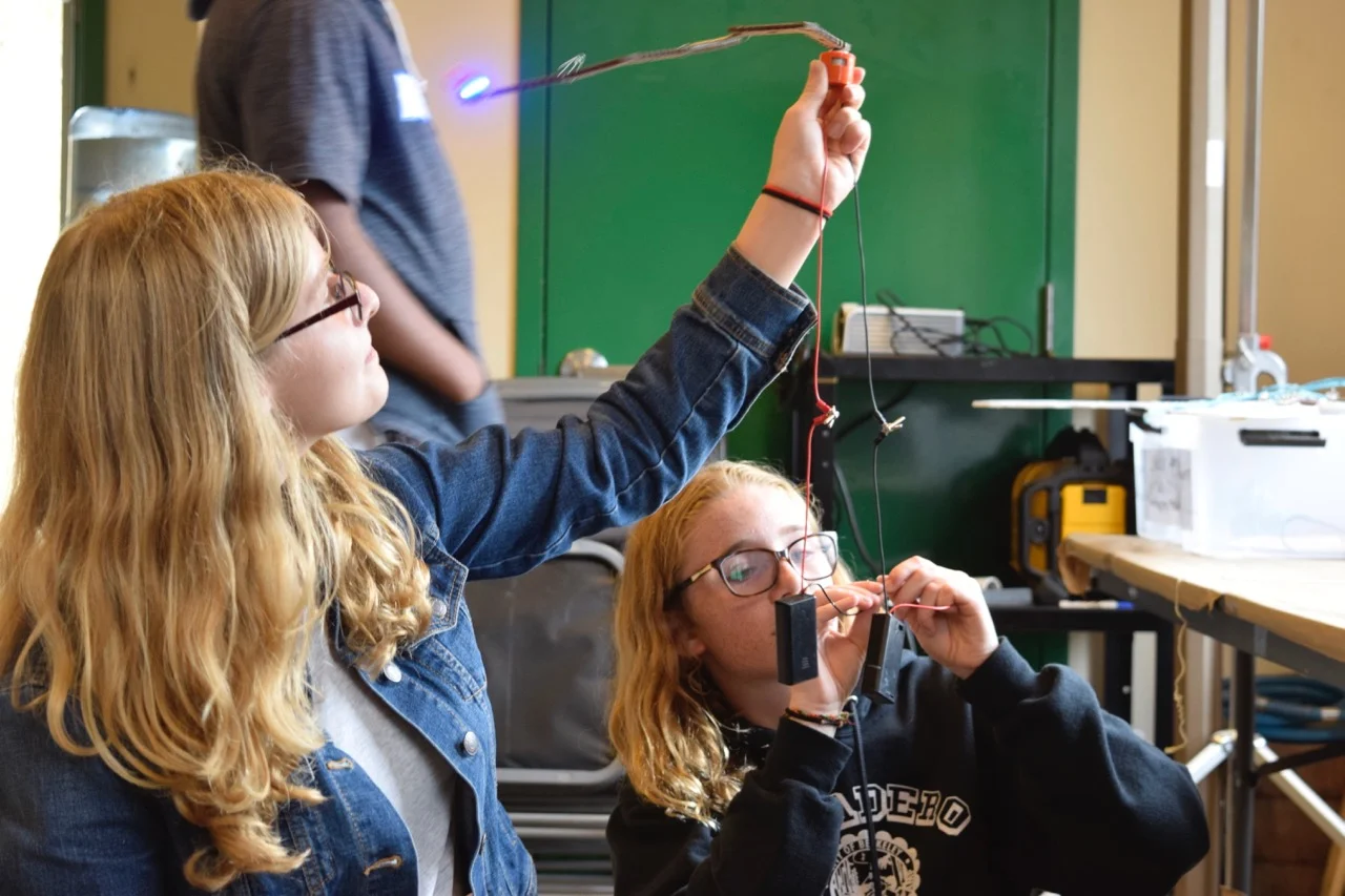 Gretchen and Sophia test a rotating contraption complete with a blue LED.