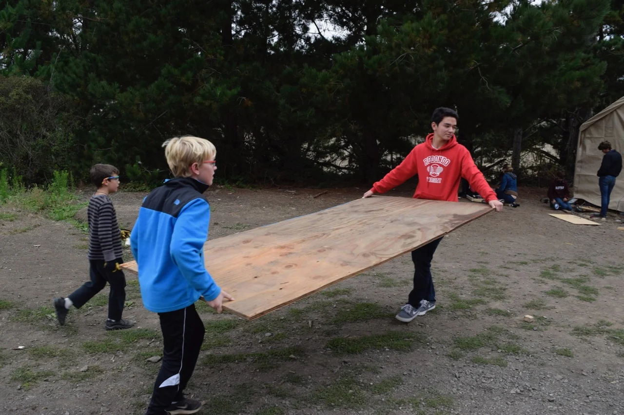 Team Panda gets some help moving a piece of ply-wood for the top of their platform.