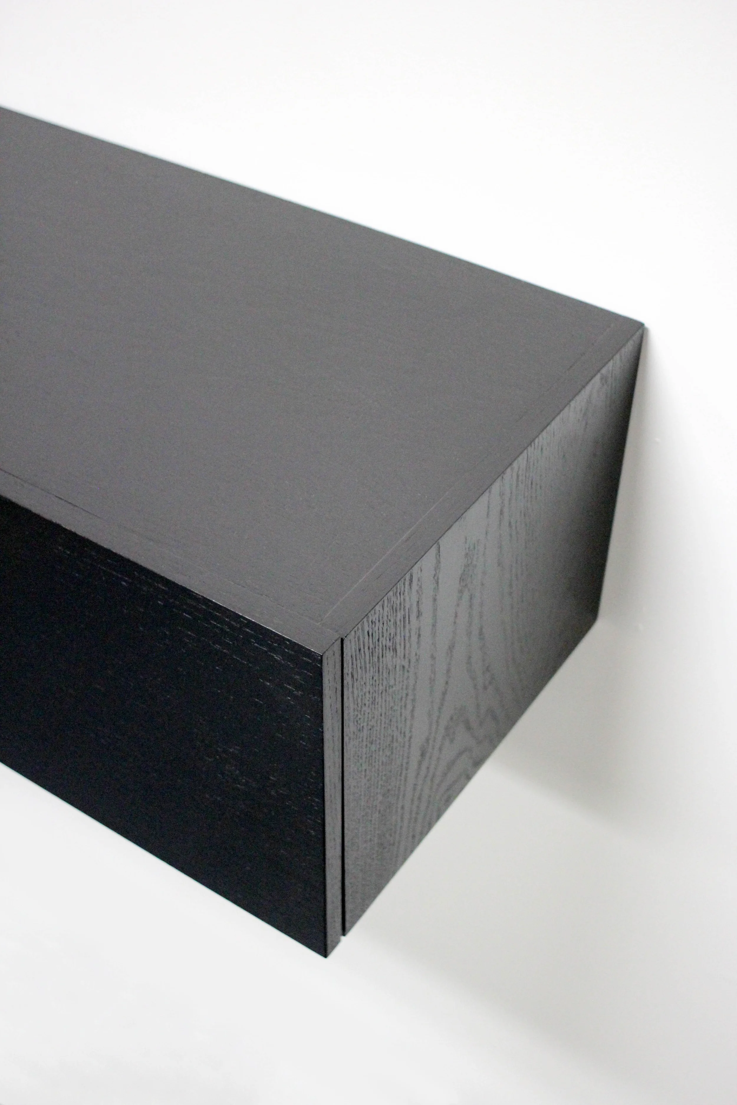 Built for a private residence in the East Village, this floating media cabinet was used to conceal the clients electronics, while also catering to their modern sensibilities. Using french cleats for wall supports and no visible hardware, it's sleek and low-profile appearance barely reads as a cabinet at all. Red oak with a satin black finish; close attention was paid particularly to the grain pattern, as it continues, uninterrupted, from one door to the other. 