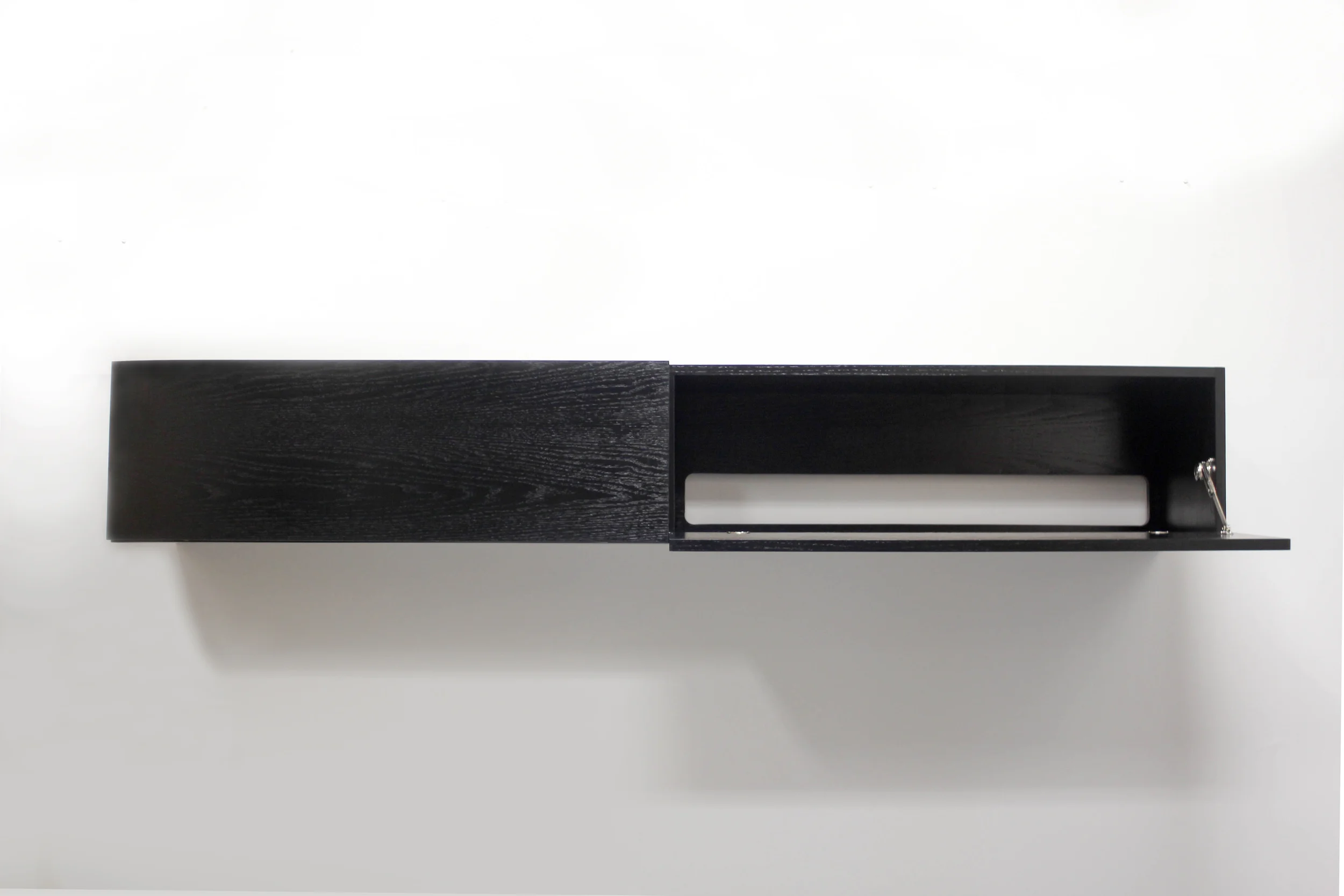 Built for a private residence in the East Village, this floating media cabinet was used to conceal the clients electronics, while also catering to their modern sensibilities. Using french cleats for wall supports and no visible hardware, it's sleek and low-profile appearance barely reads as a cabinet at all. Red oak with a satin black finish; close attention was paid particularly to the grain pattern, as it continues, uninterrupted, from one door to the other. 