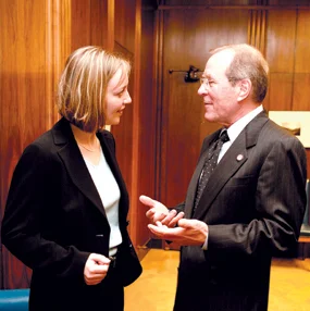 A woman and a man in suits talking to each other.