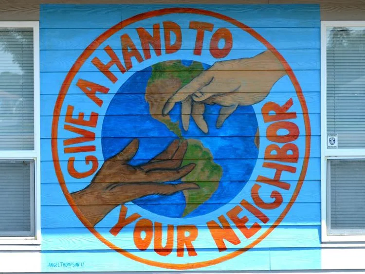 Mural reading, "Give a hand to your neighbor."