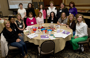A GROUP OF WOMEN POSING AROUND A TABLE.