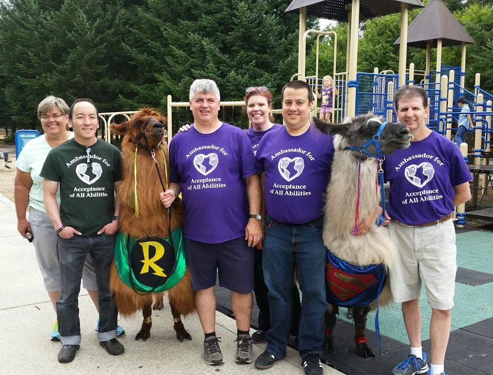 A group photo of SWWADA members, including two llamas in superhero costumes.