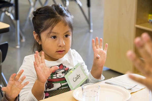 Young child with both hands raised.