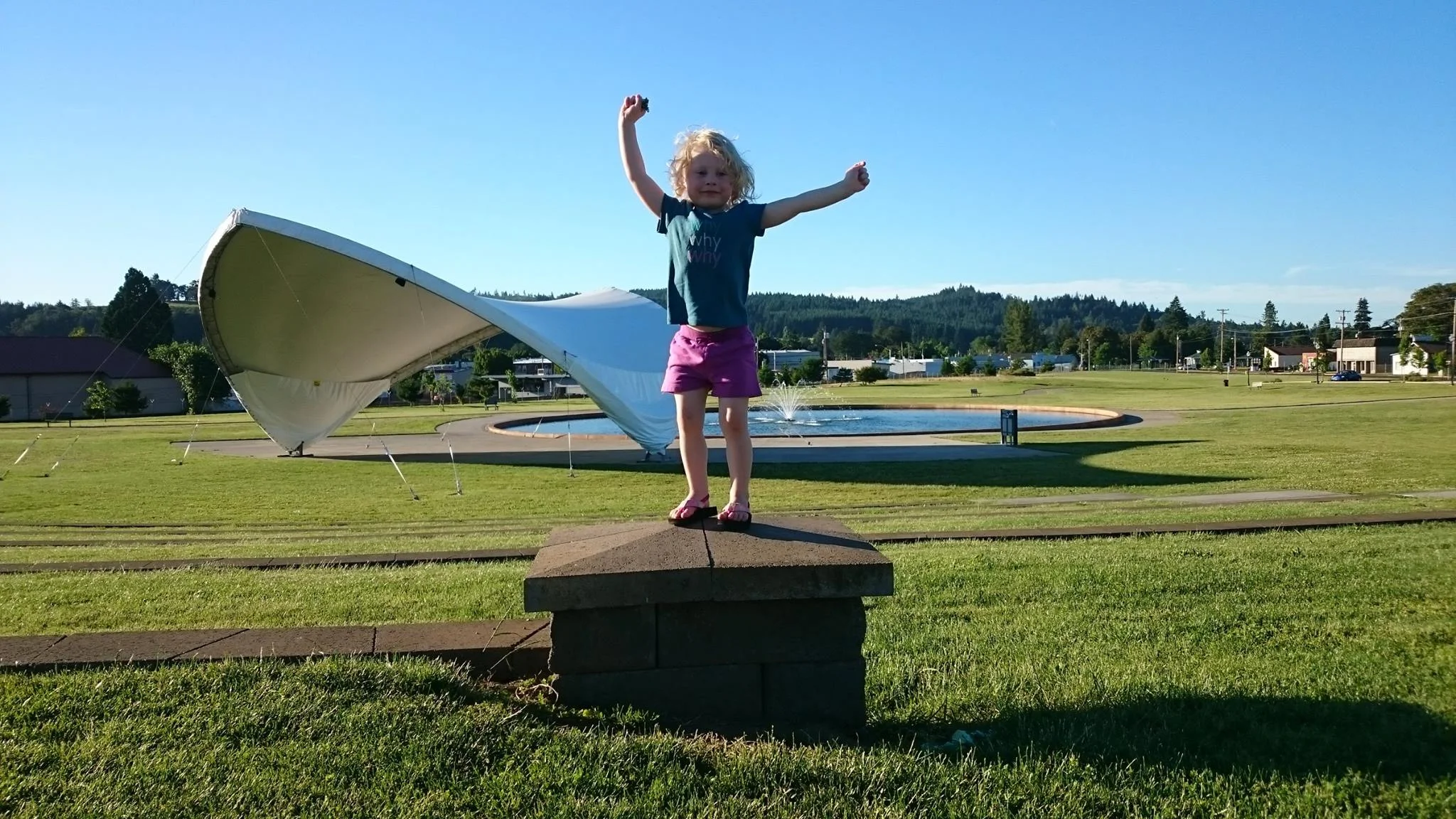 A child flailing her arms in a park.