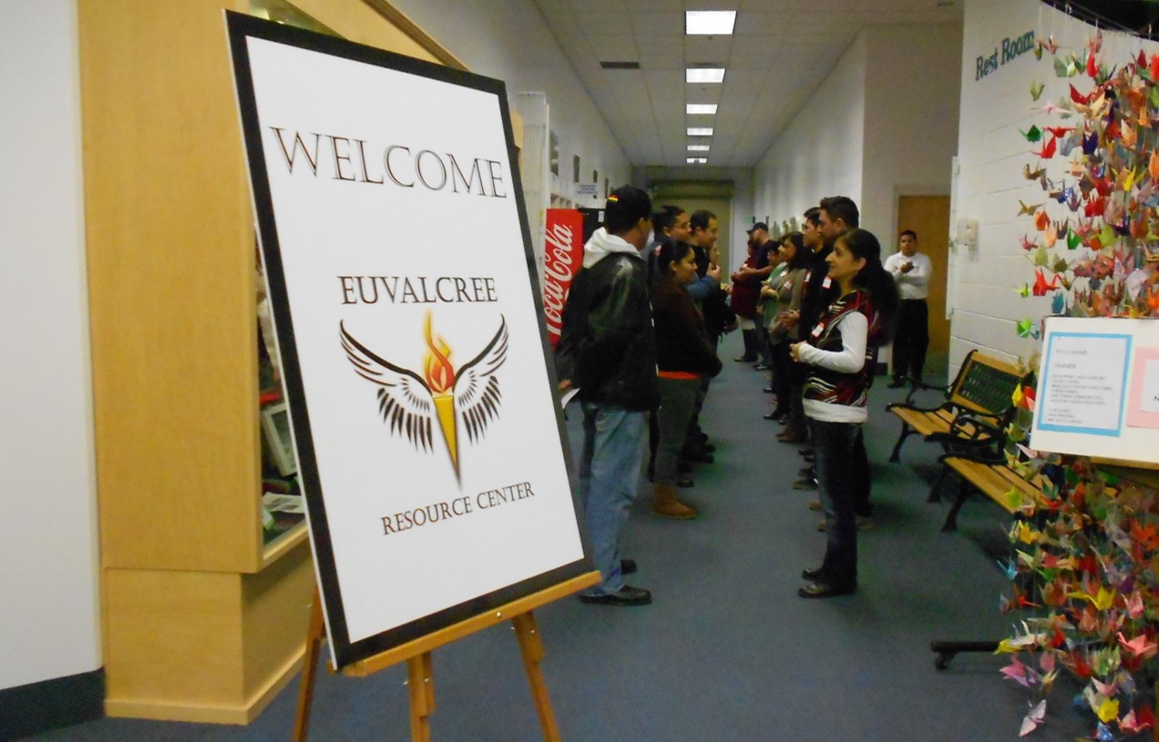 Two rows of people facing each other. A sign in the foreground reads "WeLcome Euvalcree Resource Center."