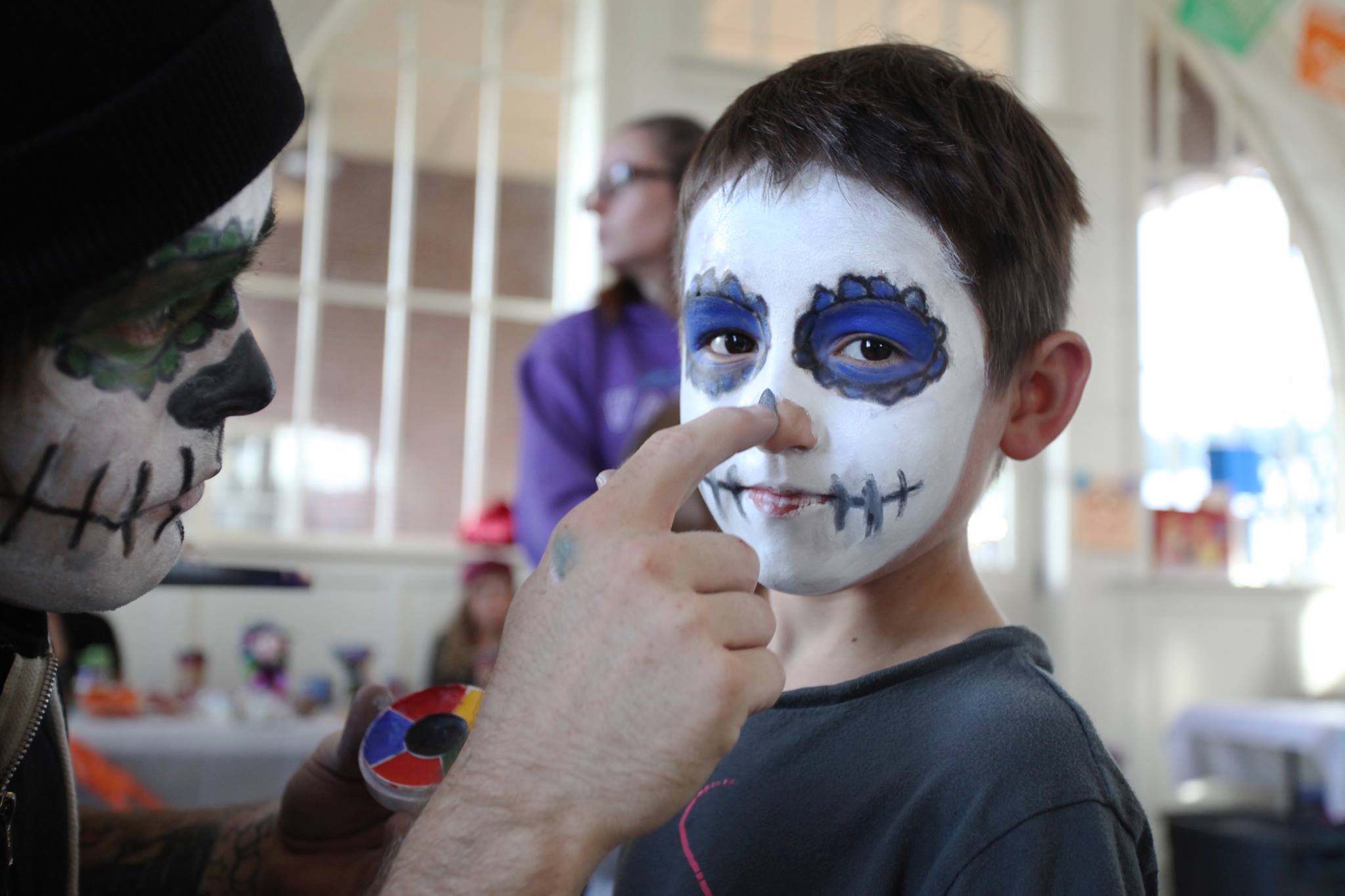 Little boy having his face painted like a sugar skull.