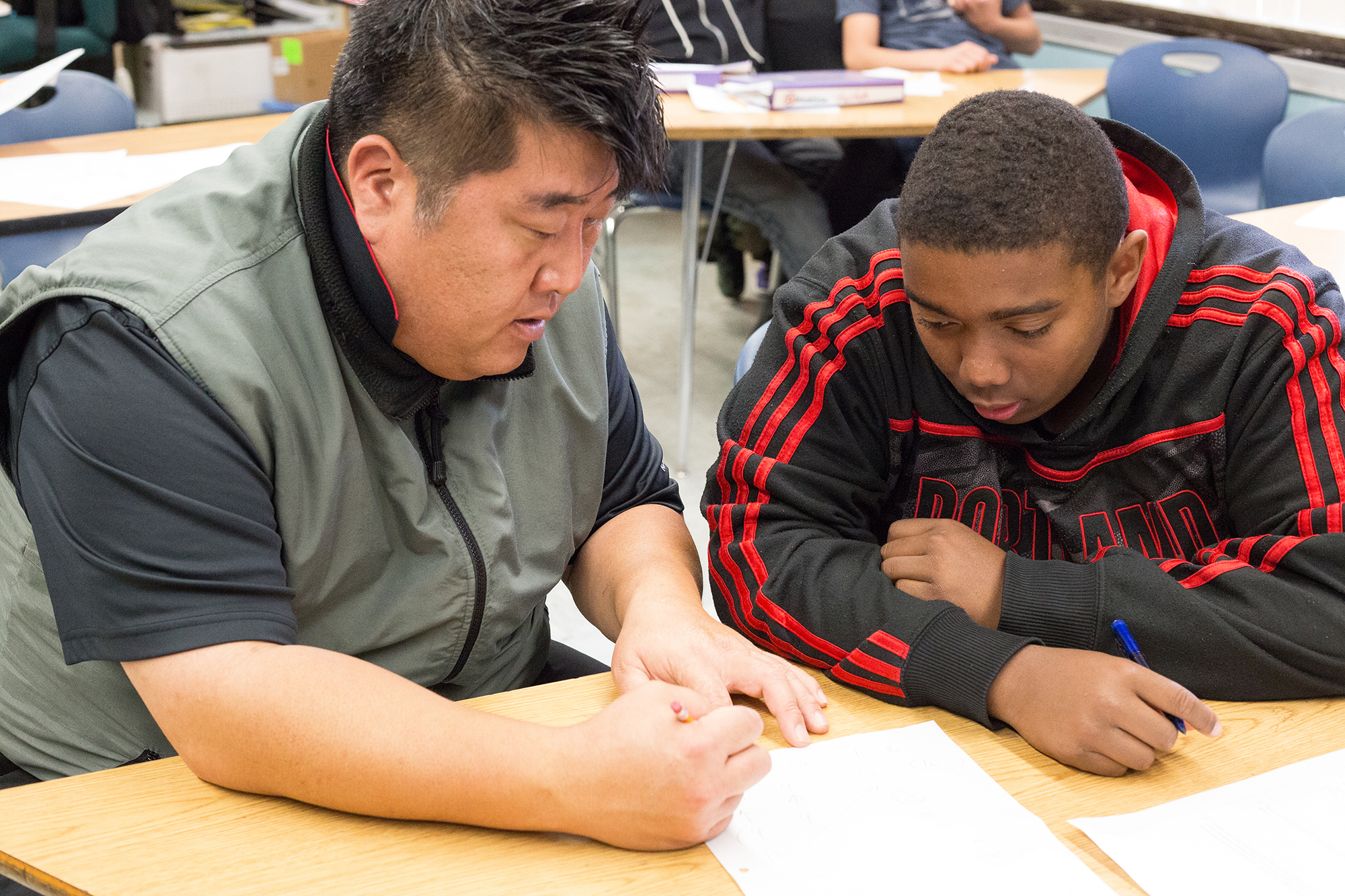 Teacher and student bending over a worksheet.