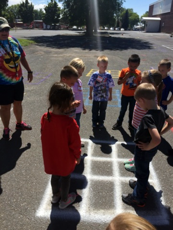 Students stand in and around a grid spray painted on a blacktop.