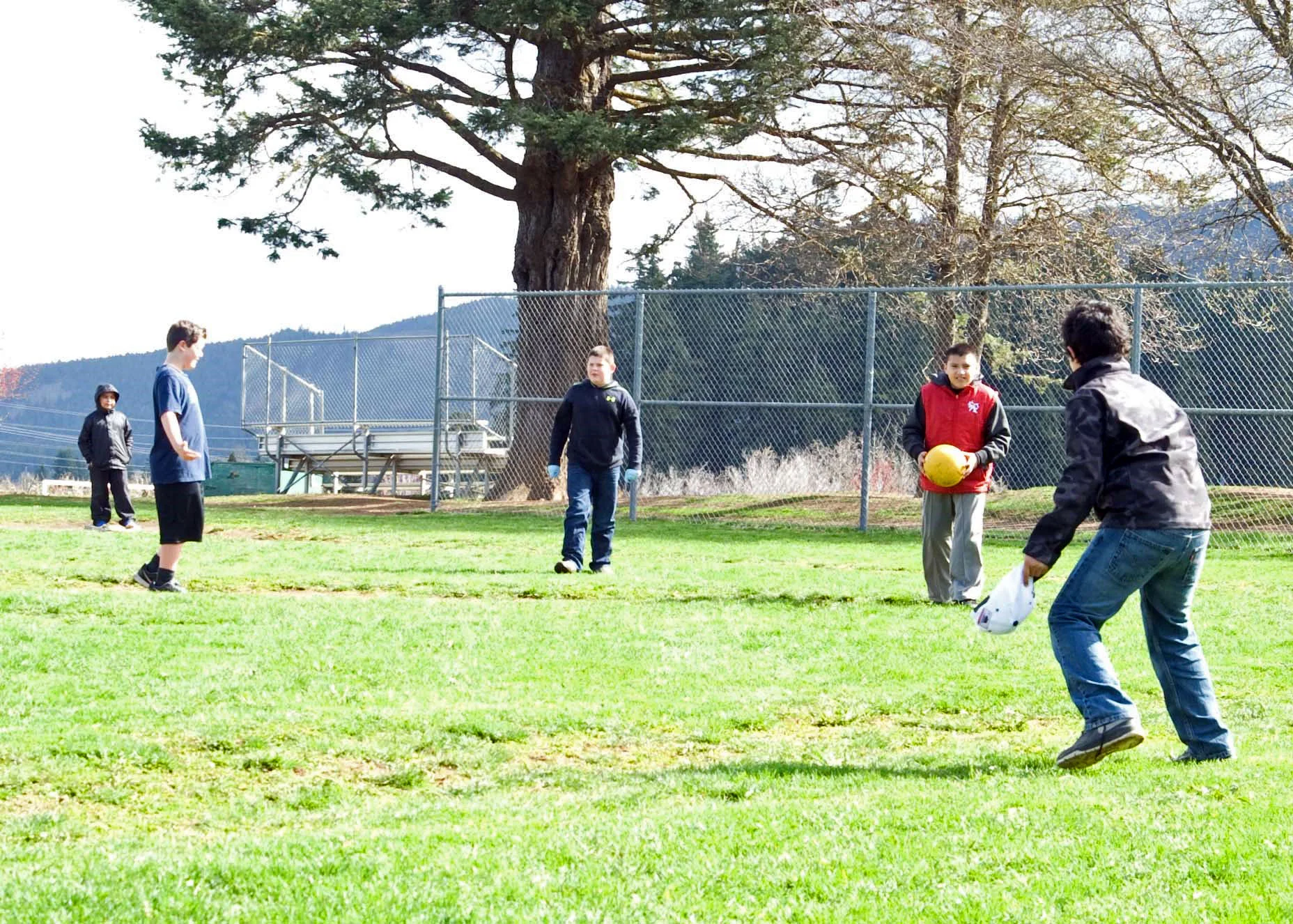 Parkdale students stand scattered around a field. One student holds a yellow ball.
