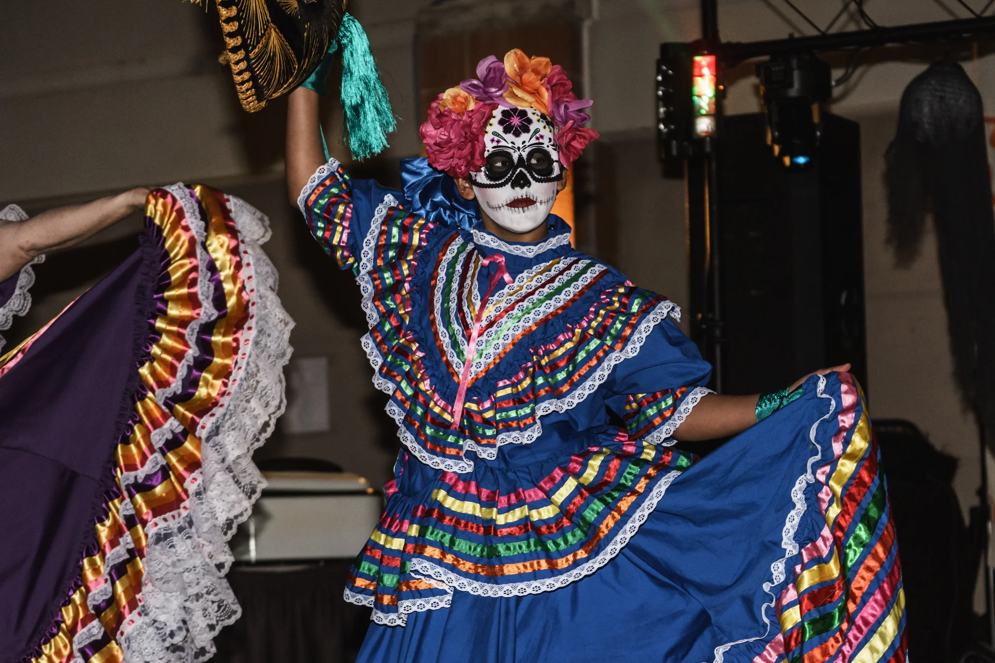 A dancer in a Jalisco dress and Sugar Skull mask performs at EUVALCREE's Day of the Dead celebration.