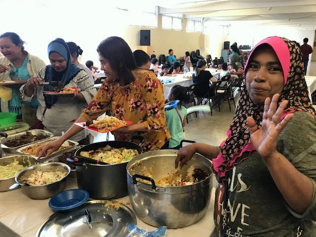 Community members serve themselves food from a buffet line.