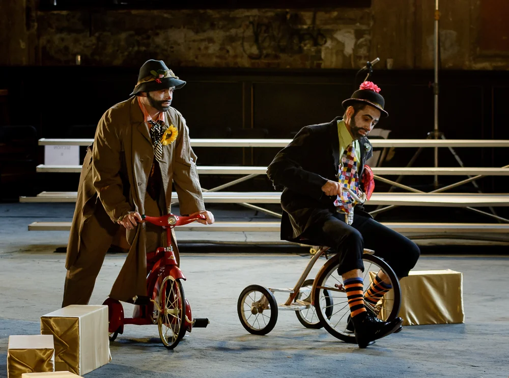 The Doctor (Gregory Purnhagen, right) and his Assistant (Ryan Glover) are transformed into clowns on tricycles.