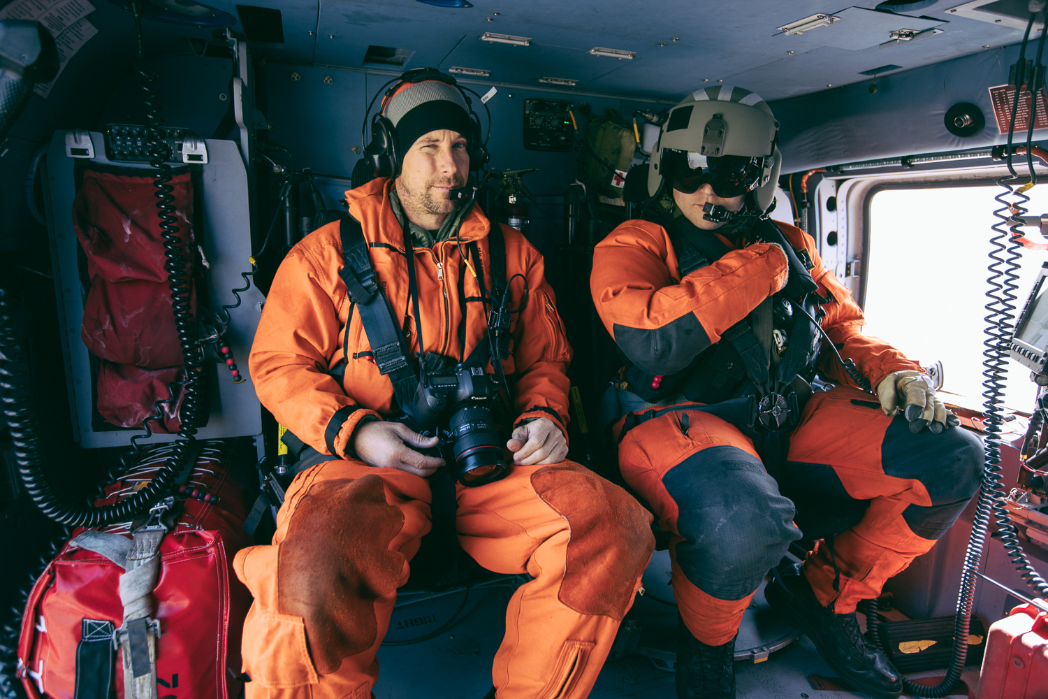Justin Bastien and Aviation Maintenance Technician Jayson Marrero flying in a USCG Jayhawk helicopter over Chinak Bay, Alaska.
