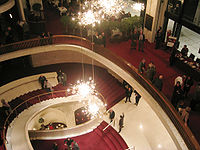 The lobby staircase of the Metropolitan Opera House today, at Lincoln Center for the Performing Arts. Photo, Wikipedia Commons.