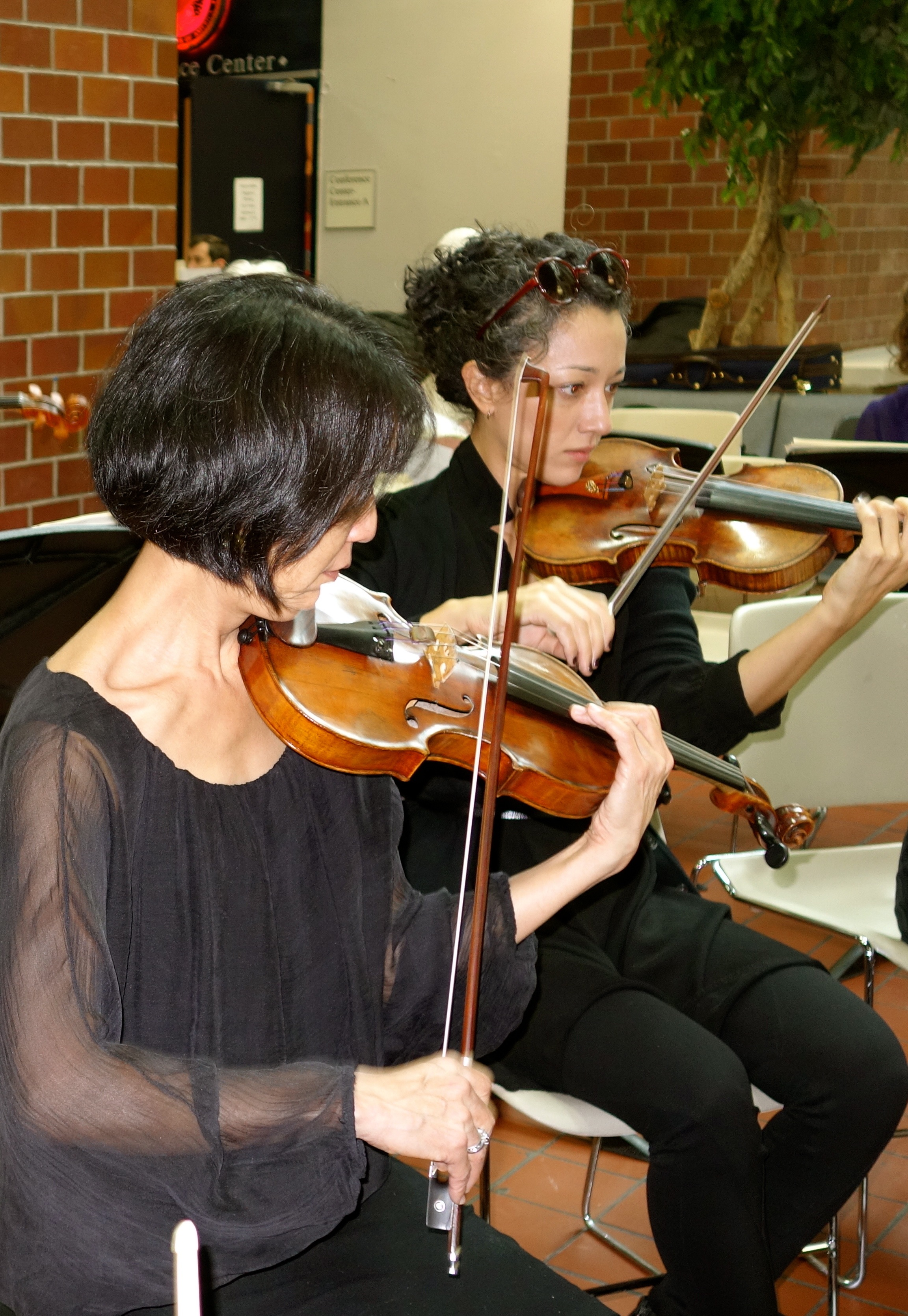 Concertmistress Nancy Wu and stand partner Toni Glickman warm up before the concert.