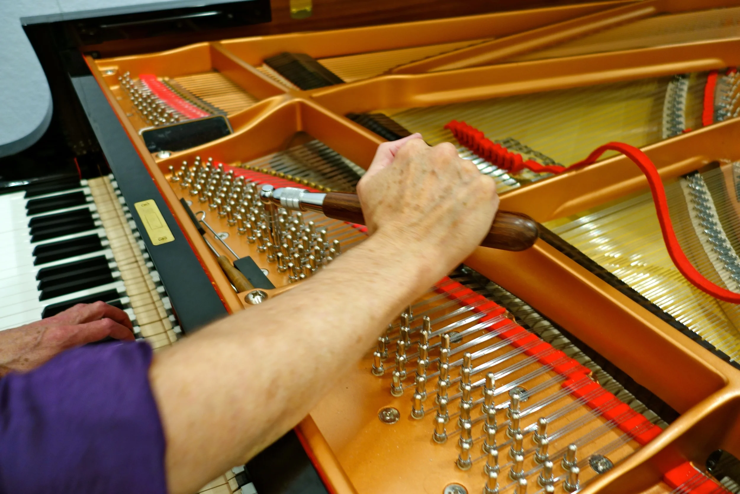 Kennedy with his tuning lever adjusting the tuning pins. Photo by Jennifer Johnson.