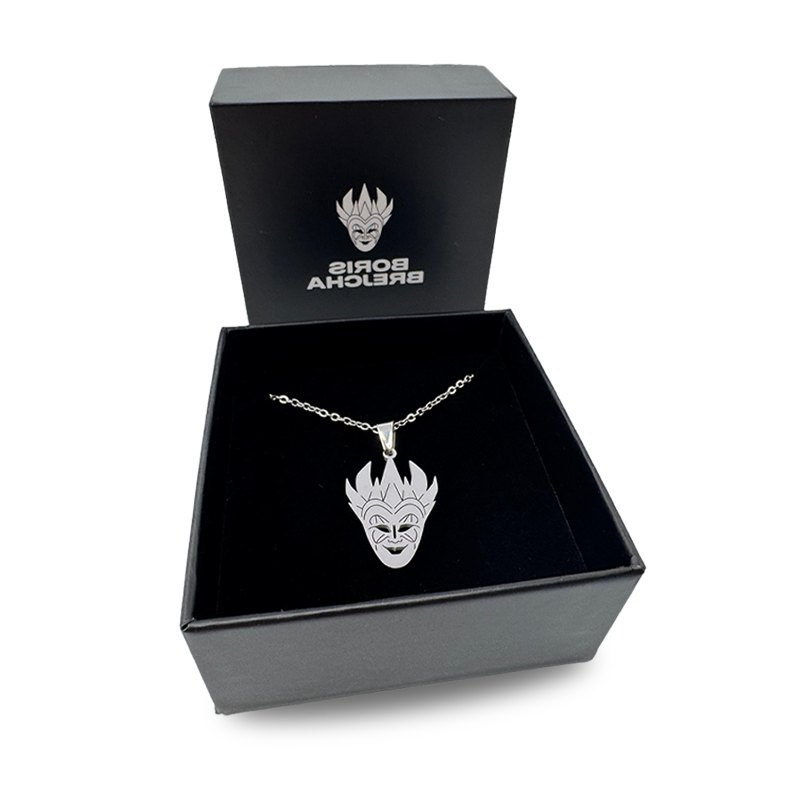 A black jewelry box with a gold chain necklace inside. The necklace has a pendant featuring a stylized, mischievous clown face with spiky hair. The box's lid, propped open, displays the text "BORDIS BRELECHA" and a logo of a clown face.