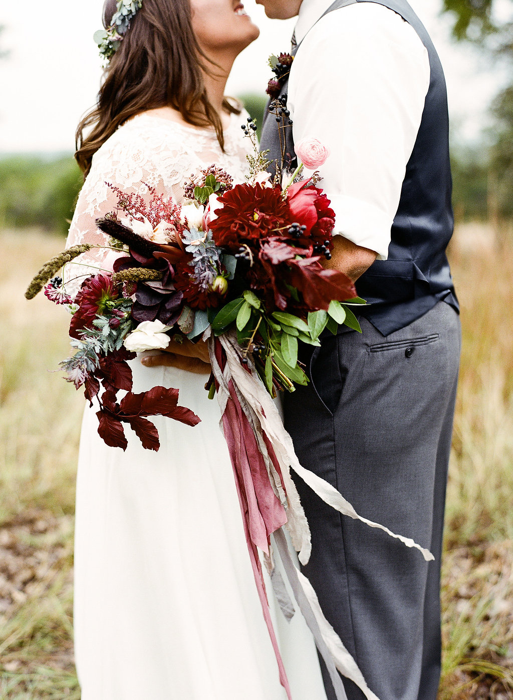  Bohemian style, red and Burgundy bridal bouquet with silk ribbon at Vista West Ranch. Petal Pushers floral event design studio located in Dripping Springs, Texas. 