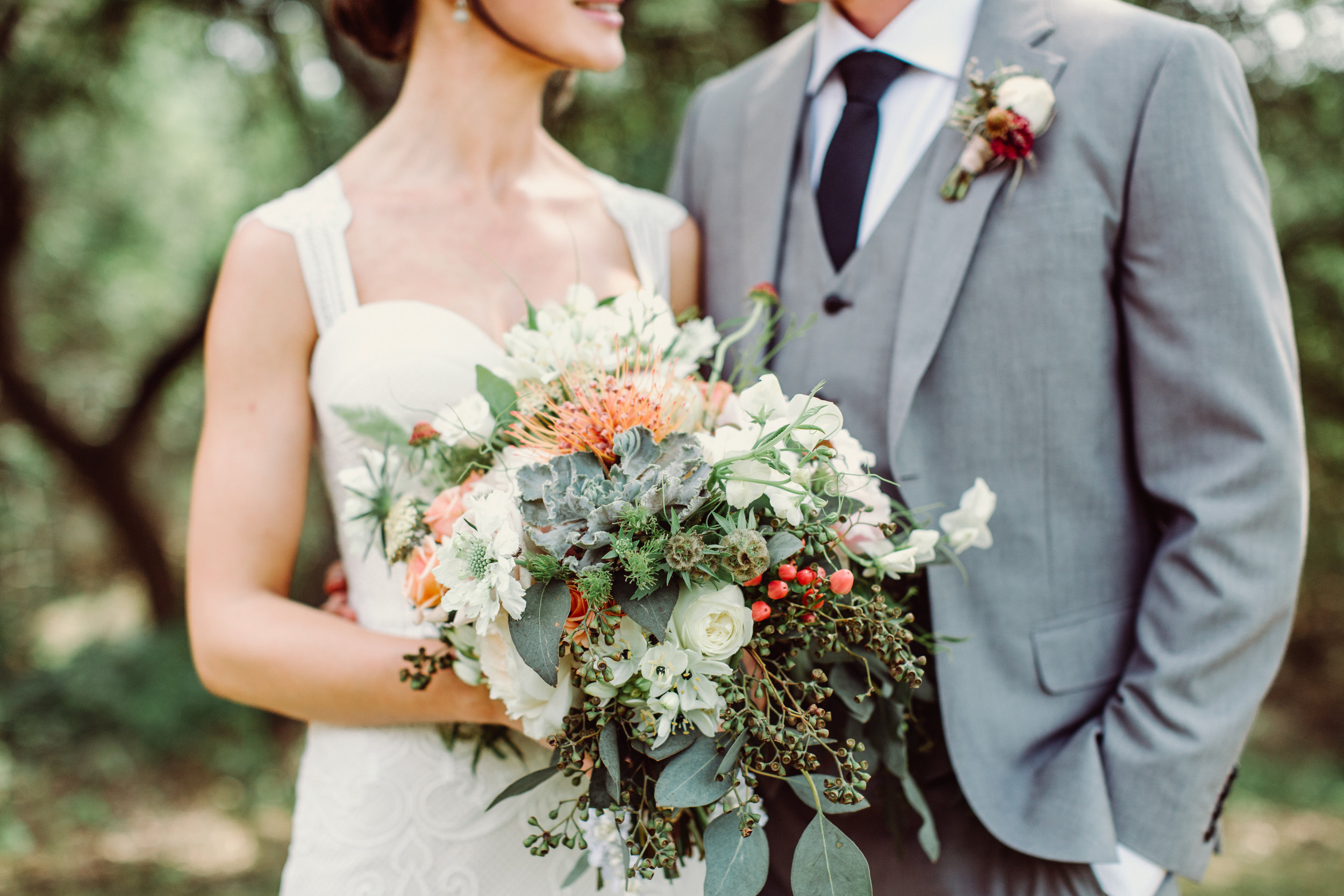  Bohemian style white with pops of orange and succulent bridal bouquet at The Creek Haus. Petal Pushers floral event design studio located in Dripping Springs, Texas. 